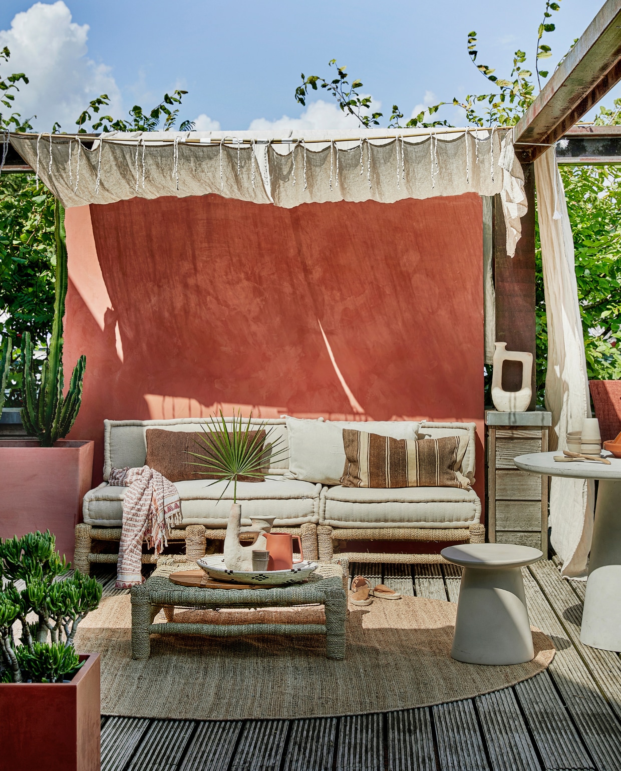 Met touw omwikkelde houten loungebank Hassan, 80x80 cm € 255,-, 120x80 cm € 335,-, zitkussens vanaf € 109,-, zandkleurige vaas Tamegroute met 2 armen € 109,-, zandkleurige vaas Tamegroute jerrycanvorm € 115,-, gevlochten schaal € 11,95, mokken en schaaltjes per stuk € 11,- (householdhardware.nl). Bruine sierkussens per stuk € 63,95, naturel geborduurd kussen Sabra Oblong XL € 99,- (zenzahome.com). Hennep vloerkleed, 250 cm (Ø) € 529,-, zandkleurige keramieken kruk Earthenware € 199,- (hkliving.nl). Espadrilles € 19,99 (hm.com). Fiberclay betonlook tafel Damon € 439,- (woood.nl). Terra karaf Flora € 21,95 (loods5.nl). Naturel linnen gordijnen Classic Sand, per stuk € 94,95 (casacomodo.nl). Hoge terra plantenbak Paris van Ecopots € 329,- (vtwonen.nl). Lage terra plantenbak € 45,- (intratuin.nl). Kalkverf op de muur kleur Marakech CC044, per liter € 52,80 (cartecolori.nl). Overig privébezit. vtwonen special tuin 06 | styling Moniek Visser | fotografie Peggy Janssen | assistentie Mirjam Gesink, Sanne Kiesling