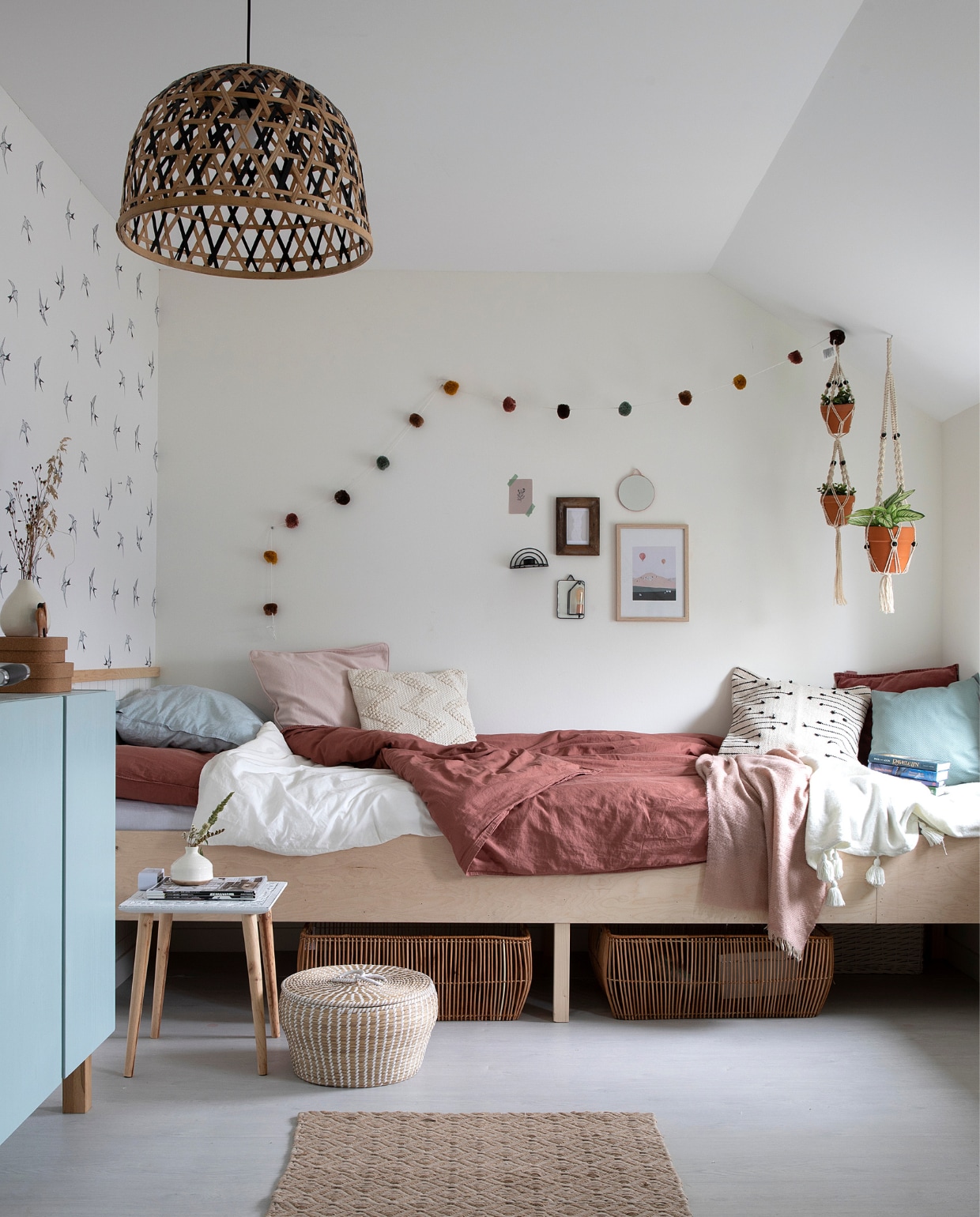 Bed gemaakt door een buurman. Beddengoed van La Redoute. Plaids Xenos. Kussens Xenos en H&amp;M Home. Lamp Kwantum. Kast Ivar Ikea. Bijzettafel Action. Behang Karwei. Pompom-slinger Zara Home. Macramé planthangers Zorgkwekerij Bloei. Manden Kwantum en Light &amp; Living. Handgeweven vloerkleed herkomst onbekend. vtwonen 08-2021 | fotografie Macha Gutlich