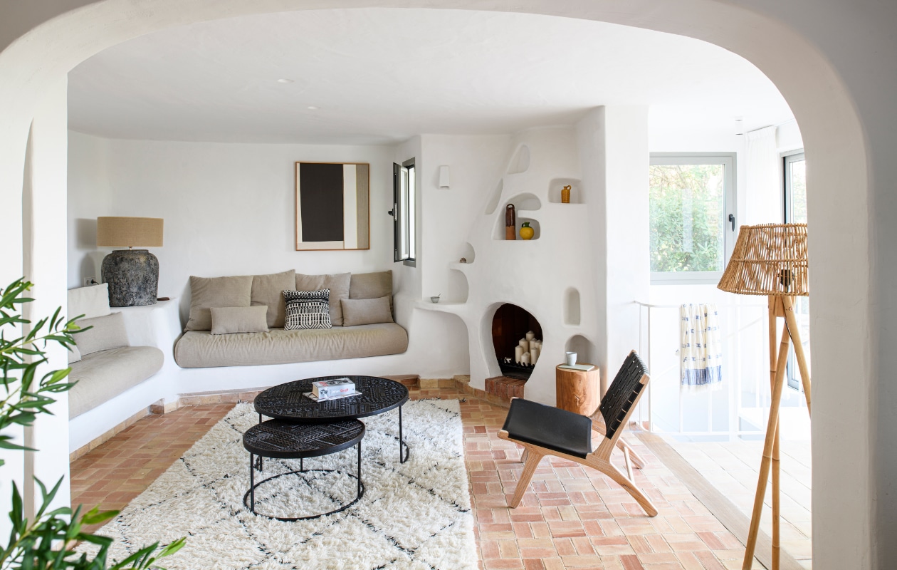 Kussen Bloomingville, vloerkleed HKliving, salontafel Ethnicraft, raamkozijn Technal, schemerlamp Vical. Vergelijkbare producten: boomstamkruk Casa Caron, fauteuil Maisons du Monde, rotan lampen Tine K Home, schilderij Naira van Kave Home. vtwonen 08-2023 | productie Insidehomepage | styling Inge van Lieshout | fotografie Louis Lemaire