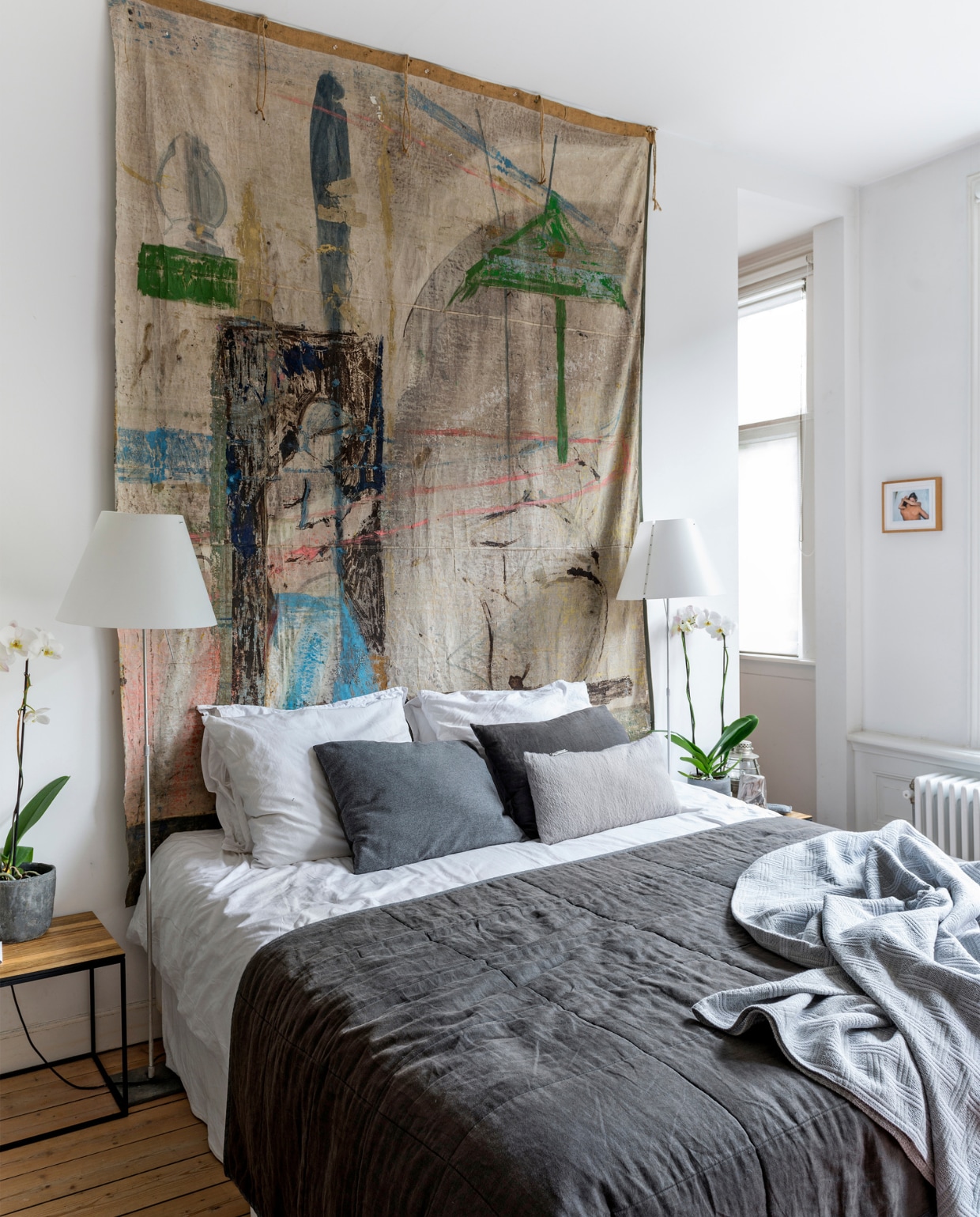 Achter het bed hangt Jaspers werk ‘Temple of the Tooth’, geschilderd op een oud theaterdoek. De foto rechts is van Martien Mulder. Het bed is van Coco-Mat. Beddengoed en sprei van Mrs. Me. Witte vloerlamp van Luceplan. De nachtkastjes zijn vintage. vtwonen 10-2016 |styling Emmy van Dantzig | fotografie Stan Koolen