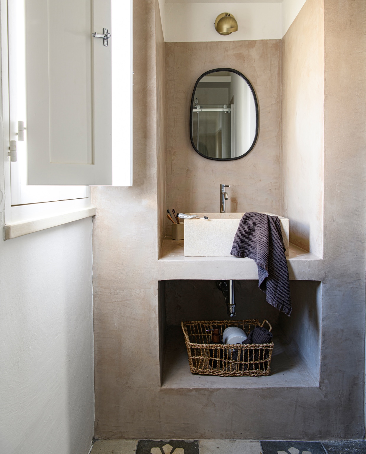 Wastafel van travertijn. Lamp Globen Lighting. Spiegel Bloomingville. Verfkleur North Sea Silt van Pure & Original. Overig onbekend. vtwonen special binnenkijken 06-2023 | productie Insidehomepage | fotografie Louis Lemaire | styling Marit Saladini