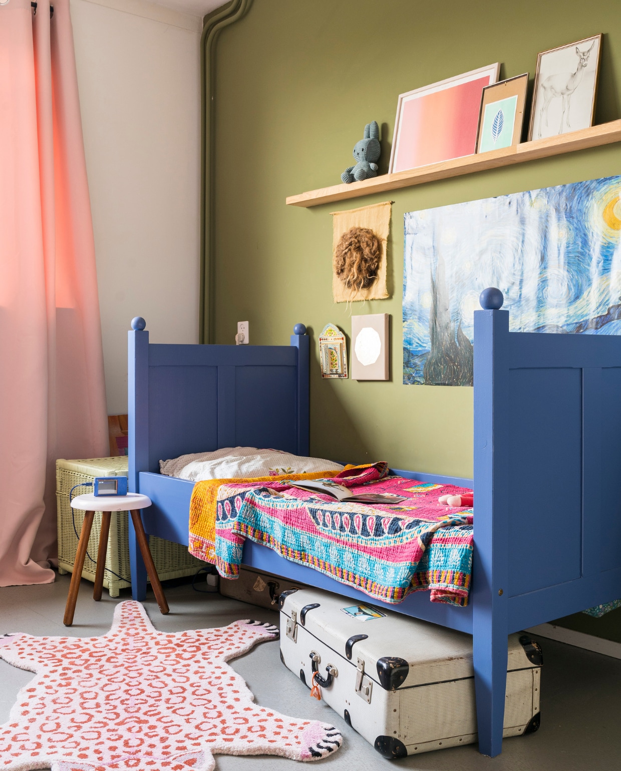 Verfkleur wand Olive van Farrow &amp; Ball. Verfkleur bed Ultra Marine Blue van Farrow &amp; Ball. Gordijn van La Redoute. Bed Marktplaats. Kantha-kleed uit India. Panter Doing Goods. Spiegeltje met deurtjes uit Marokko. Goudkleurige maan IrisDorine. Vilten Maan Halona. Van Gogh-poster Desenio. Op de plank Nijntje, soortgelijk bij De Winkel van Nijntje. Roze print Eveline Renzenbrink. Prent met veer We are out of office. Hert kringloopwinkel. Wekkertje geprogrammeerd door Timo. Beddengoed Hema. Plank herkomst onbekend. Overige kringloopwinkel. vtwonen 07-2021 | fotografie Muk van Lil