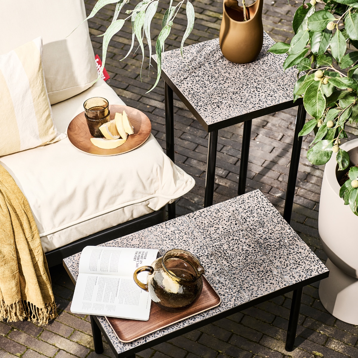 Modulaire loungeset Paletti van Fatboy, kunststof frame met waterafstotende kussens € 899,-, bruine stenen vaas Nicita van Bloomingville € 58,90 (vtwonen.nl/shop). Plaid € 12,99, blauw gestreept kussen € 17,99, geel gestreept kussen € 17,99, glazen karaf € 29,99, houten onderzetter € 5,99, houten dienblad € 17,99, drinkglazen € 5,99 (zarahome.com). Overig privébezit. vtwonen 08-2023 | styling en uitvoering Sanne Ketelaar | fotografie Sjoerd Eickmans