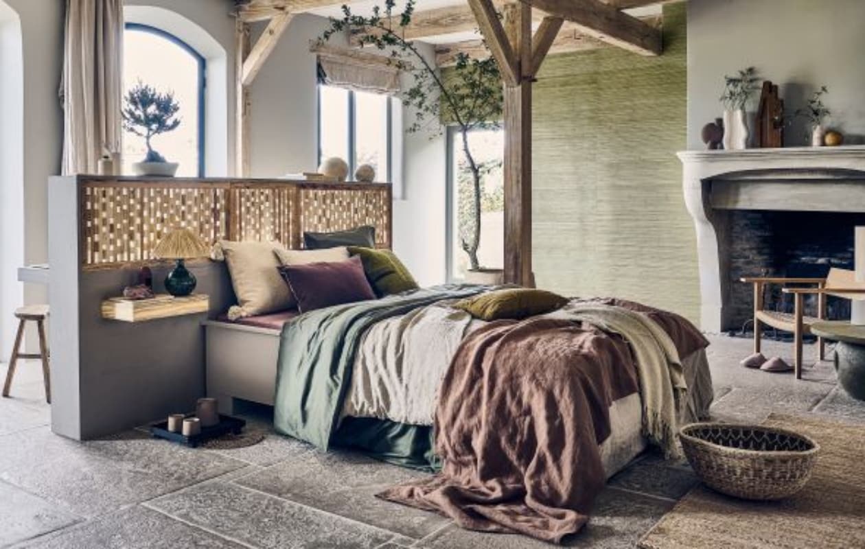 Op maat gemaakt bed van Combitex prijs op aanvraag (com-anders.nl). Papieren behang Natural Wallcoverings 3 in 303519, 550x91 cm (lxb), per rol € 160,- (eijffinger.com). Houten melkkruk € 155,-, naturel Lozi mand uit Zambia € 115,-, groene glazen tafellamp € 229,-, bruine handgeweven waaier nr. 4 € 36,-, groen kelim kussen uit Turkije, wol en katoen € 49,- (couleurlocale.eu). Zwart eikenhouten dienblad € 115,- (fermliving.com). Witte aardewerken vaas Moire van Ferm Living € 139,-, katoenen plaid van Malagoon in Clay White, 152x127 cm € 39,95 (vtwonen.nl/shop). Bonsai Pinus € 20,85 (plantje.nl). Ecomix object Calcolo, set van 2 € 84,95 (urbannatureculture.com). Witte inktpot op bedrand € 15,99, witte vaas met kwasten prijs op aanvraag, wit blad op nachtkast € 39,99, paarse kussenhoes € 29,99, ecru linnen kussen € 15,99 (zarahome.com). Ecru katoenen kussen met pompon € 19,99, loper voor bed, 70x200 cm € 99,- (hm.com). Aardewerken vaas Sphere Bubl van 101 Copenhagen € 52,95,-, paarse matrashoes van Yumeko € 109,95, beige linnen dekbedovertrek van Yumeko € 329,-, donkergroen katoensatijnen dekbedovertrek van Yumeko € 109,95, bijbehorende kussenhoes € 29,95 (debijenkorf.nl). Keramieken koppen op dienblad, per stuk € 16,95, keramieken theekan € 18,95 (lanena-home.com). Steen op nachtkast prijs op aanvraag (splitkorrel.nl). Groen kussen € 69,- (sukha.nl). Overig privébezit. vtwonen 2023-09 | Styling Liza Wassenaar, assistentie Lila Steijger, Judith Koers, Kula Isabelle Den Broek | Fotografie Sjoerd Eickmans