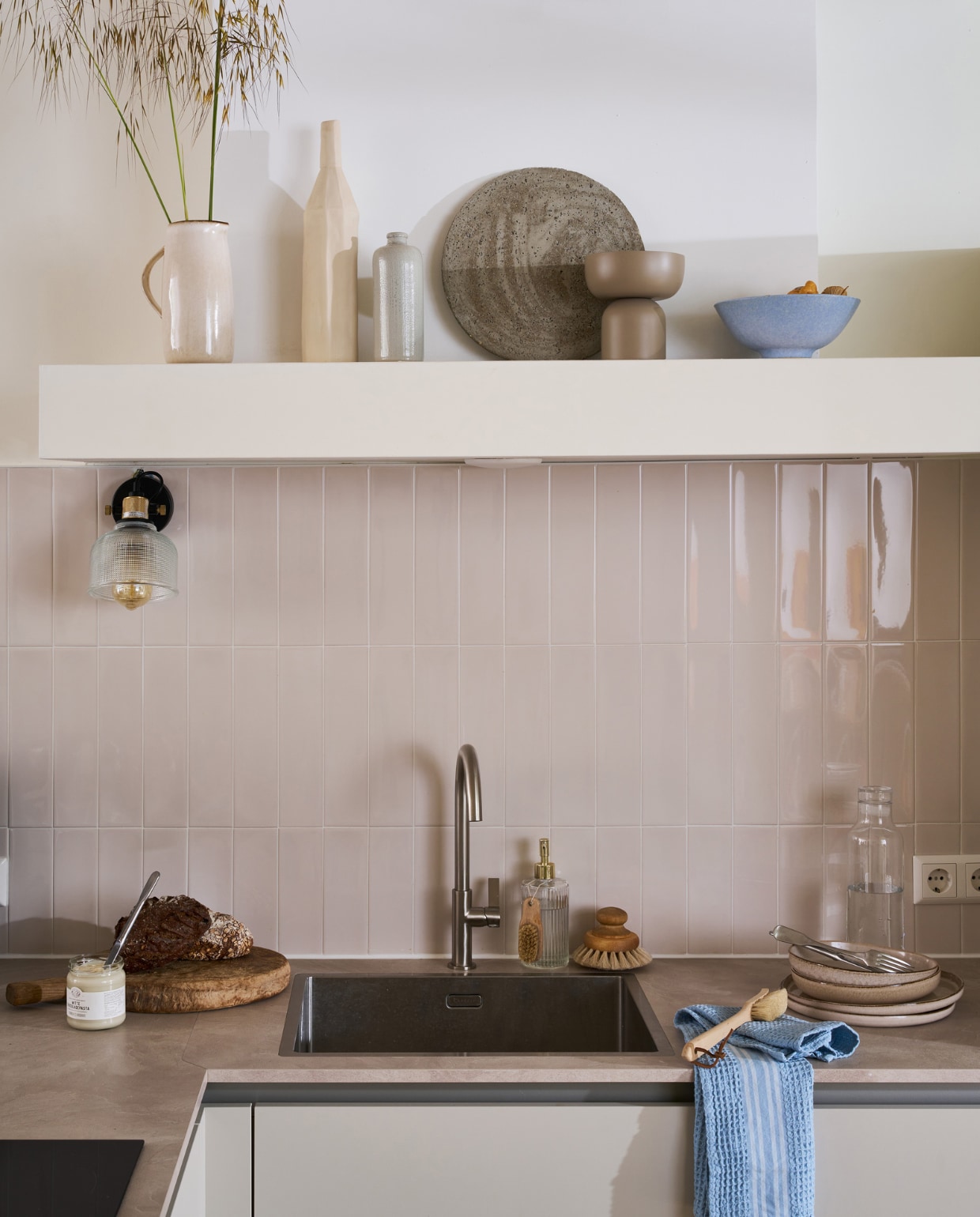 Composiet spoelbak met goudkleurige kraan, prijs op aanvraag. Wandtegels Shapes in Vapor van vtwonen, 7,5x30 cm, per m² € 59,-. M.m.v. hm.com (kom, borden, theedoek, schaal op voet, kan), bolia.com (karaf). Overig privébezit. vtwonen 09-2023 | productie Tanja Saarberg | styling Cleo Scheulderman | fotografie Jeroen van der Spek