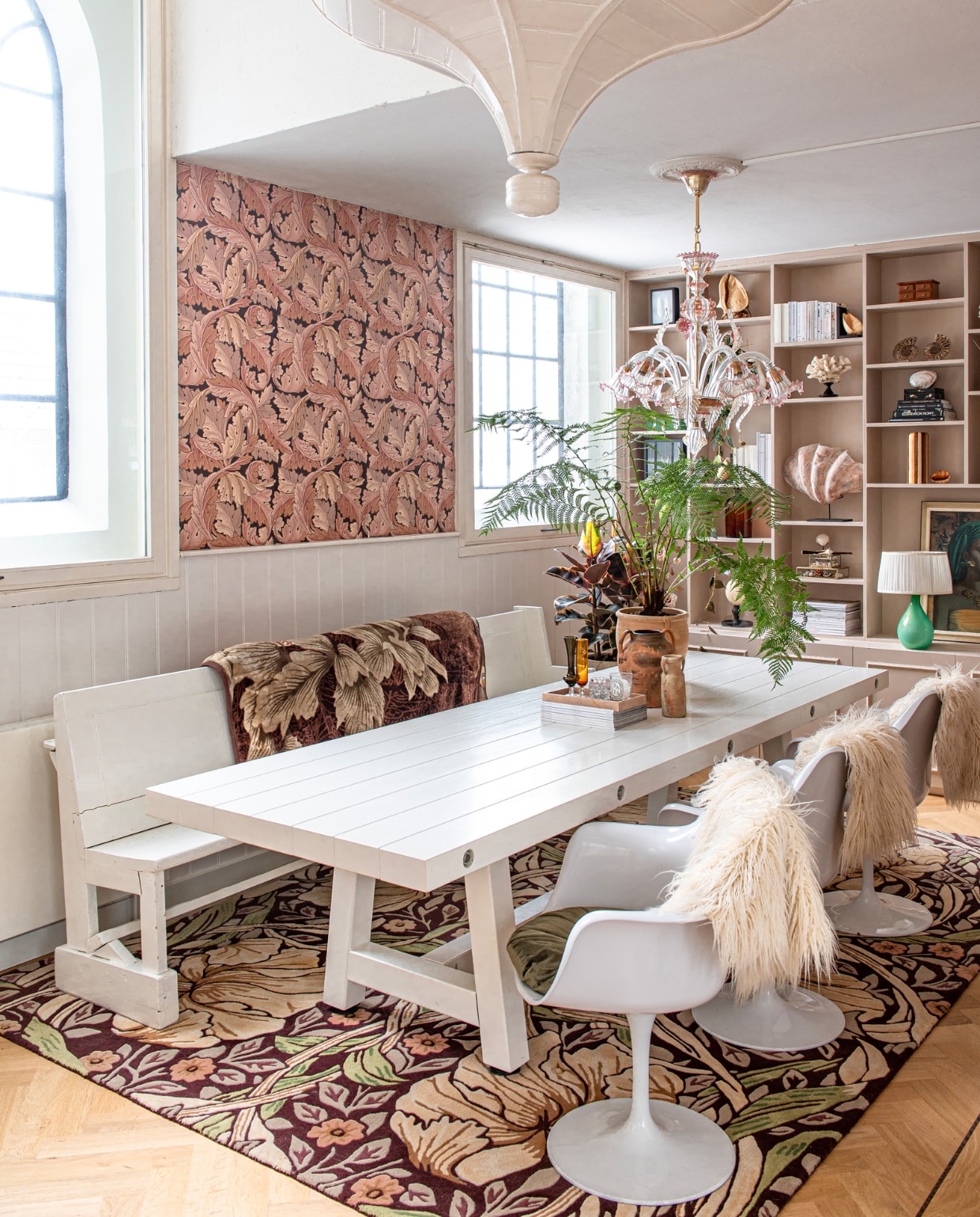 Tafel, stoelen en schapenvachten Loods 5. Kussens in stoelen laten maken, behang en vloerkleed William Morris, kerkbank Marktplaats, kroonluchter van Murano-glas uit Italië, wandkast laten maken, in de kast vintage en souvenirs. vtwonen 09-2023 | productie De Binnenkijkers | styling Jeske Weel | fotografie Caroline Coehorst