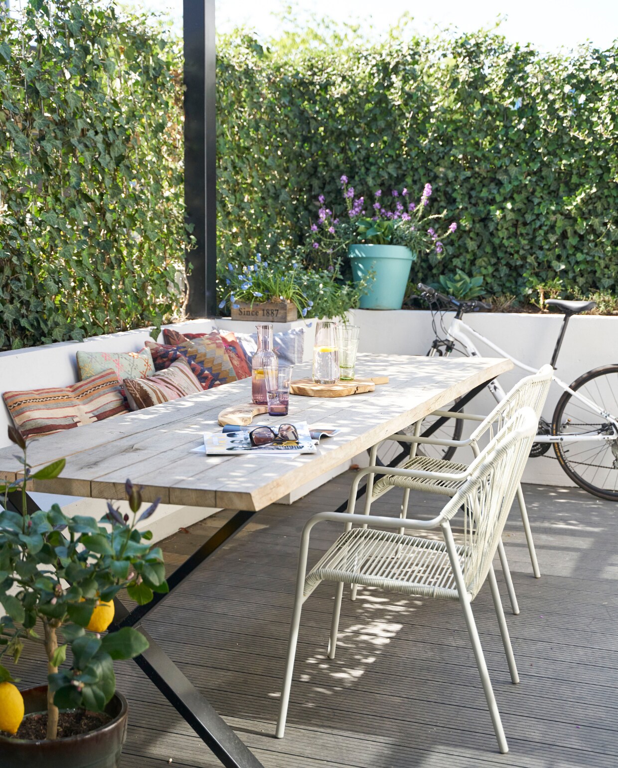 Tafel Gewoon Wonen, stoelen Karwei, kelimkussens Bohemian du Maroc. Glaswerk Ikea. Ingebouwde bank, metalen pergola met ingebouwde verlichting (ook te gebruiken om een schaduwdoek aan te bevestigen) en planten­bakken eigen ontwerp en op maat gemaakt. vtwonen 08-2020 | productie Features &amp; more | styling Wilma Custers | fotografie Luuk Geertsen