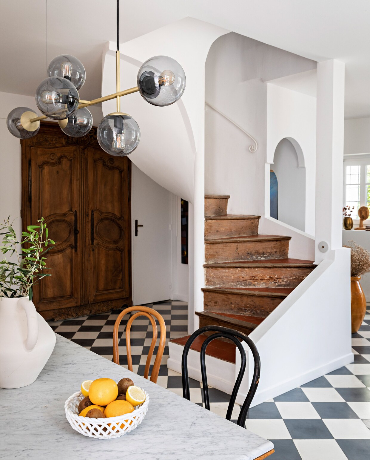 Tafel La Redoute. Stoelen erfstukken. Hanglamp Bolia. Vaas rommelmarkt. Fruitschaal Monoprix. Oude houten deuren, tegels en trap zaten al in het huis. vtwonen special binnenkijken 06-2023 | productie &amp; styling Marie Maud Levron | fotografie Yann Deret