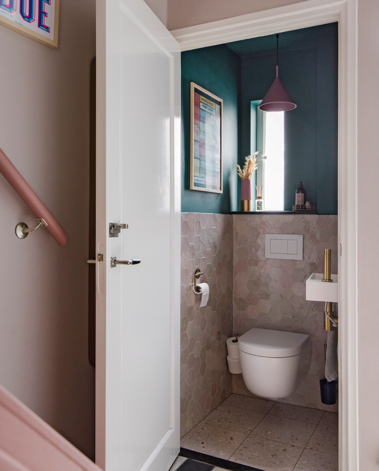 Tegels toilet Zellige Hexagone in Gris Rose van Designtegels. Toiletwastafel met gouden kraan Ink, muurverf Forest Green van Lab Paint, hanglamp Triangle van HKliving, poster Mary Go Wild. Roze trap geverfd in Terra Pink van Lab Paint. vtwonen 09-2023 | styling Luka Jacobs | fotografie Corine hoge Bavel-Jansen