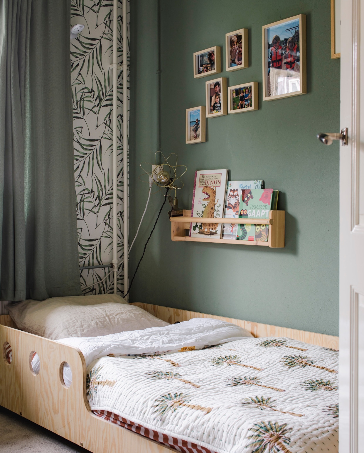 Behang Feline en hanglamp Boreas van Kwantum. Bed Marie van Petit Puk, babydeken Original Palm van Unknown Stories, hoeslaken Studio Ditte. Wandopberger Flisat en fotolijsten van Ikea. Vloer en gordijnen waren al aanwezig. vtwonen 09-2023 | styling Luka Jacobs | fotografie Corine hoge Bavel-Jansen