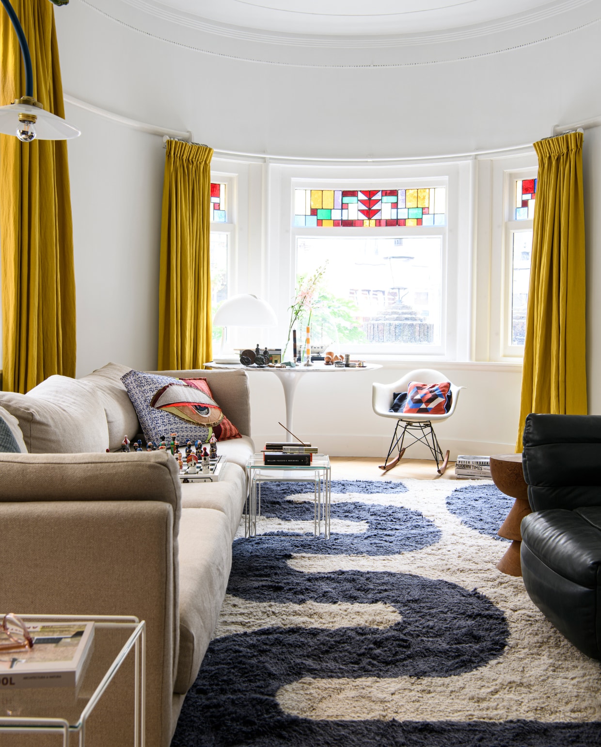 Schommelstoel Eames van Vitra, tafel Tulip van Saarinen, vloerkleed Zakaria Rugs, gordijnen gemaakt met stof van de markt. Overig onbekend.