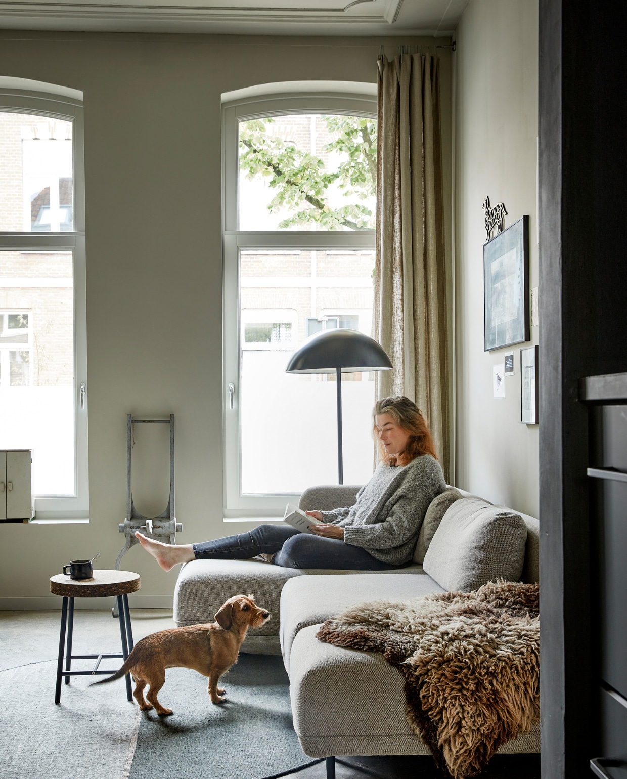 Mees en Muis. Zandcementen dekvloer met 2-componenten hoogglanscoating. Bank Ellis Sofacompany. Plaid en schapenvacht gekregen. Vloerkleed Magnetize Linie Design. Kruk Sinnerlig en vloerlamp Ikea. Het ornament tegen de muur is een houten mal van ontwerper Faas van Dijk. De grote foto aan de muur is gemaakt door Mees’ vader. Print musje OpTekening. vtwonen  binnenkijken special 03-2022 | productie &amp; styling José Martens | fotografie Peggy Janssen