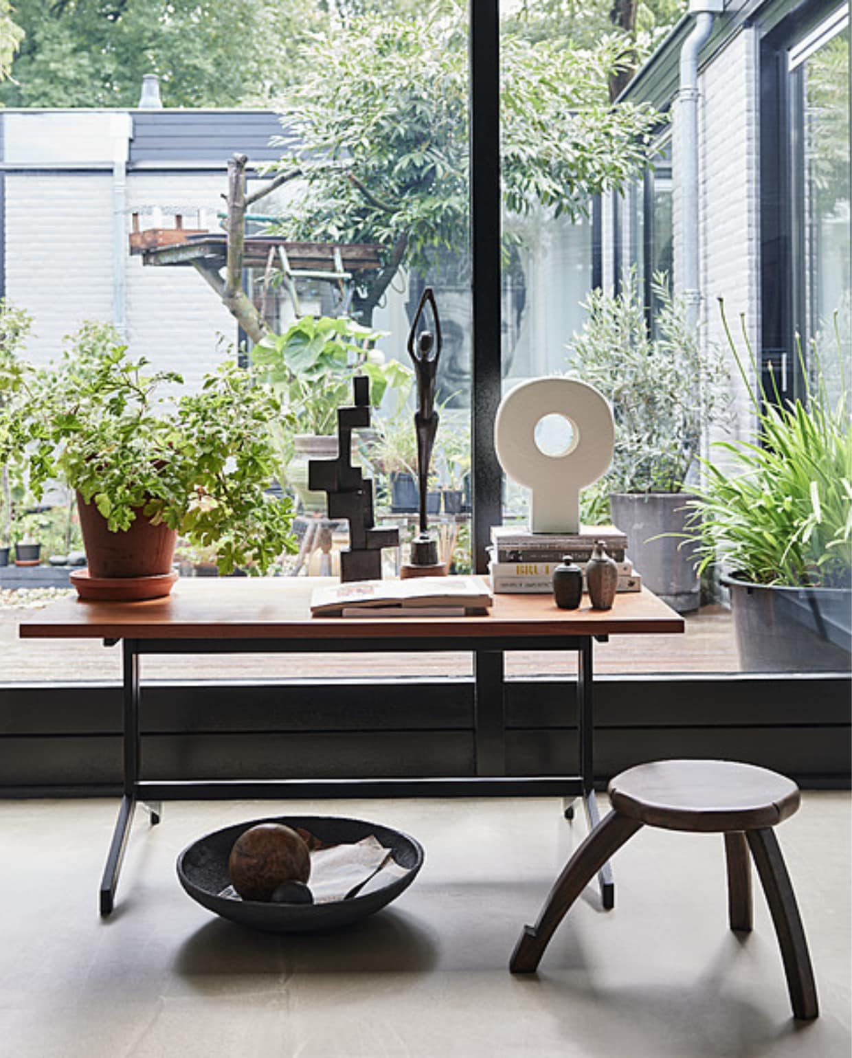 Vintage salontafel Eeka van Friso Kramer en Coen de Vries, 120x65x53,5 cm (lxbxh) _ 175,- (neeflouis.nl). Keramische tafellamp Tree _ 99,95, zwart metalen object Aosta _ 119,-, stenen schaal Atelj_ _ 22,95, mangohouten plantentafel, 50x28 cm (_xh) _ 159,- (urbannatureculture.com). Beeld, souvenirs, houten bal en overig priv_bezit. vtwonen 2023-10 | Styling Fietje Bruijn | Fotografie Alexander van Berge