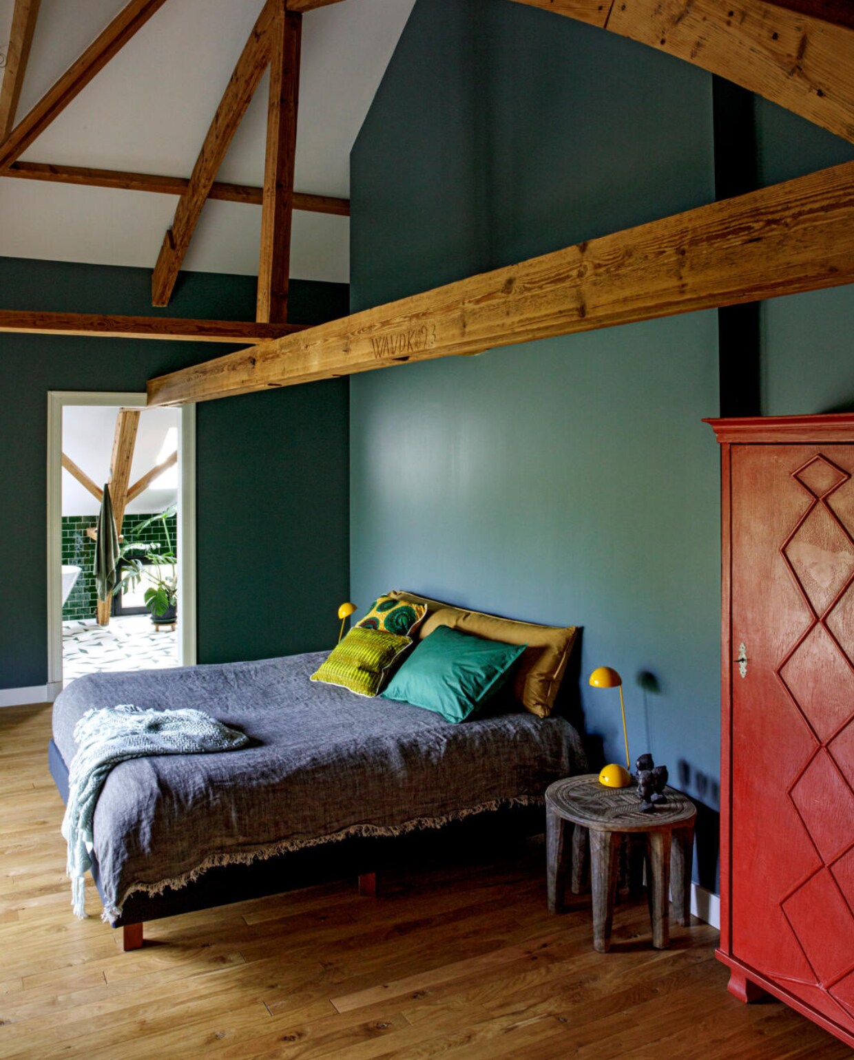 Eikenhouten vloer De Oude Plank. Muurverf Inchyra Blue van Farrow &amp; Ball. Kast Van Dijk &amp; Ko, bijzettafel uit Nigeria, lang kussen Bedmate Suite702, effen kussen Suite702. Vintage bed en gele lampen markt, herkomst spreien en overige kussens onbekend. vtwonen 10-2020 | fotografie Inga Powilleit | styling José Martens
