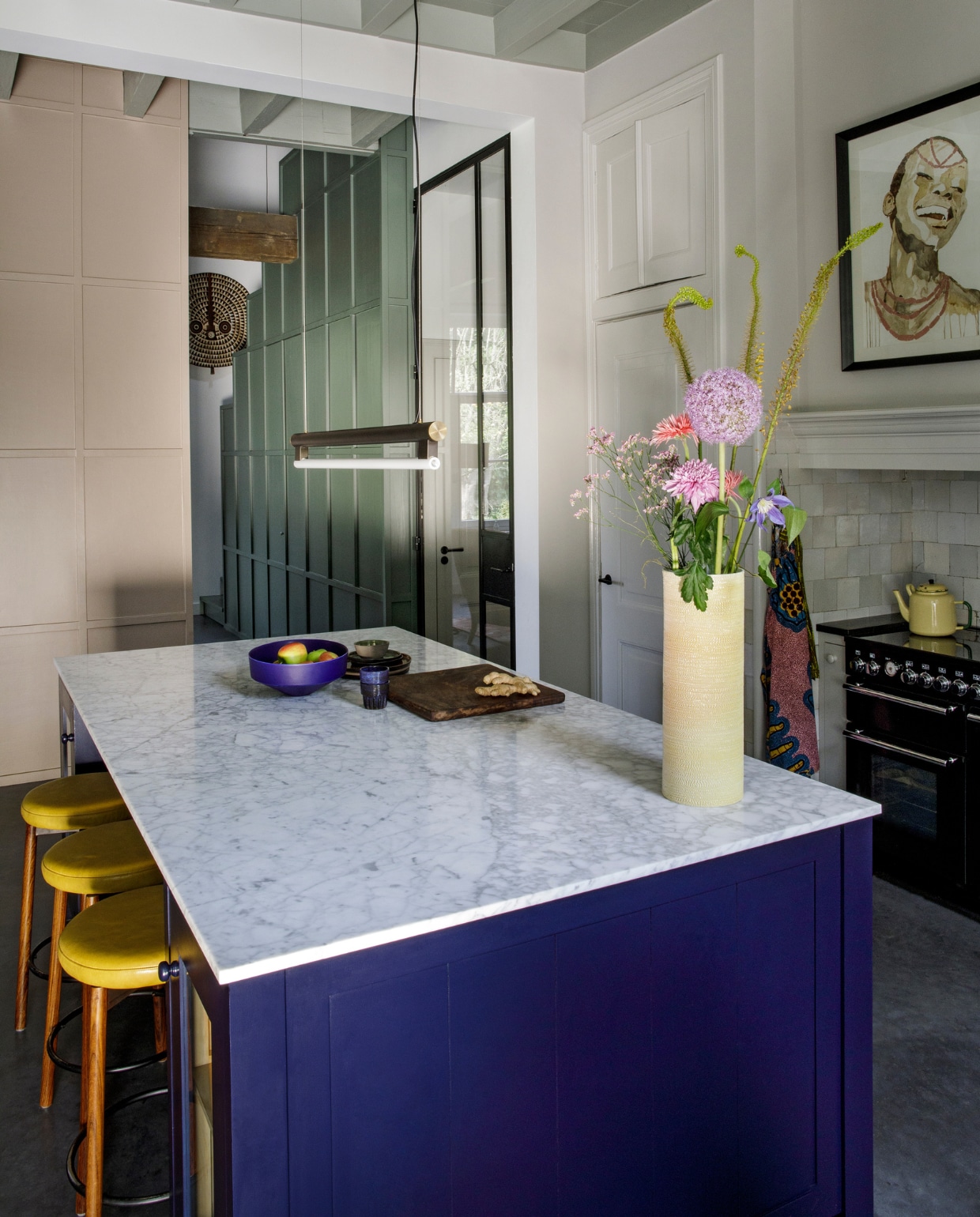 Keukenontwerp Mirte, gebouwd door Martens &amp; Dochters. Marmeren blad Revy Stone. Krukken Morentz, lamp Frama, vaas Studio Truly Truly, fruitschaal Geert Lap, aardewerk Claudy Jongstra, blauwe mokjes Mella. Fornuis Falcon. Schilderij, houten masker, houten plank, theedoek, theepot uit Nigeria. vtwonen 10-2020 | fotografie Inga Powilleit | styling José Martens