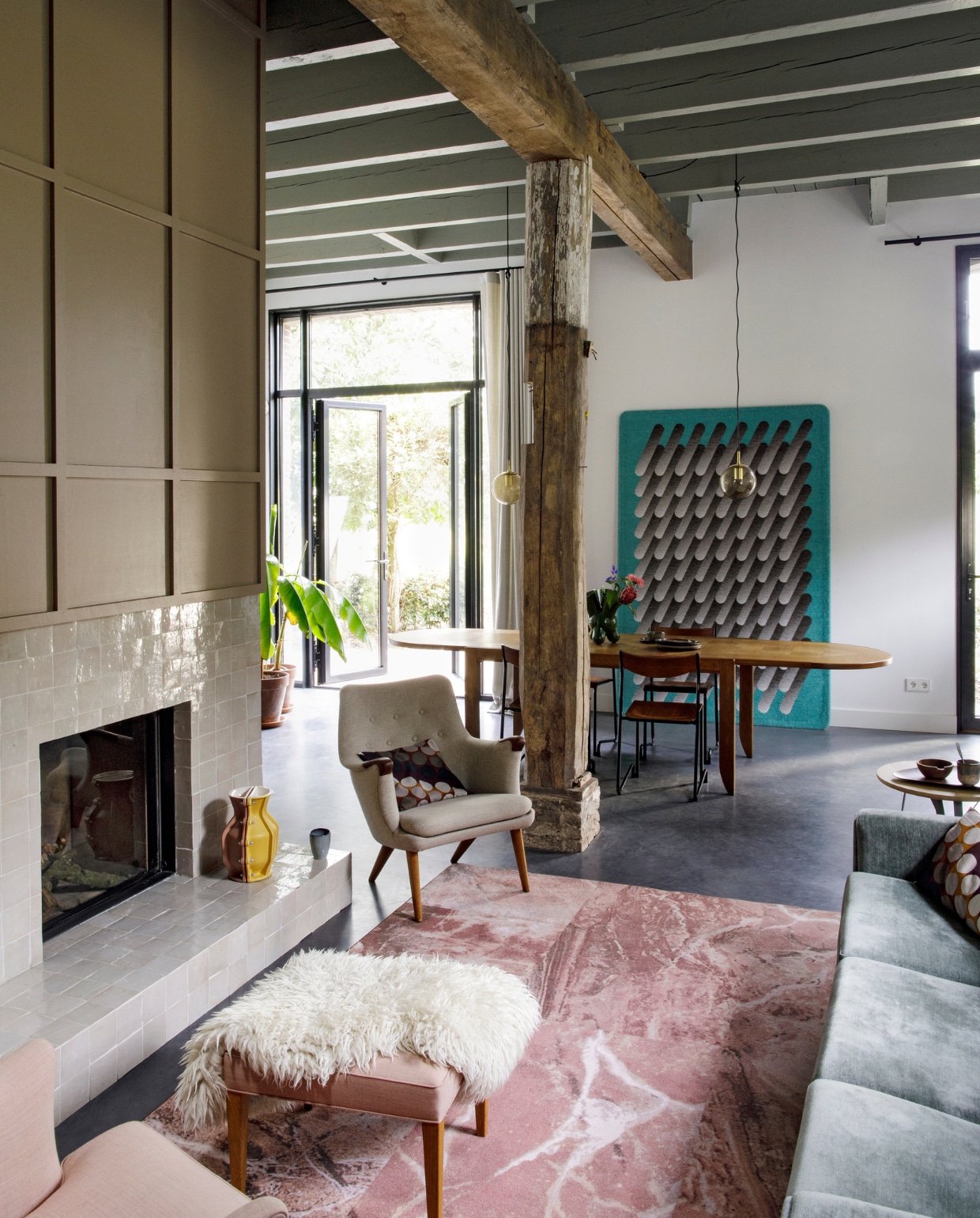 Tegels haard Rozetta, vaas Studio Truly. Verf boven haard Dead Salmon van Farrow & Ball. Vaas Floris Hovers. Kussen gemaakt van vintage De Ploeg-stof. Vloerkleed Sense of Marble van Desso. Bijzettafel Twister van Spoinq. Betonvloer Willem Designvloeren. Vintage fauteuils, voetenbank, eettafel, stoelen, hanglampen Morentz. Wollen wandobject en plaid Sigrid Calon. Schapenvacht lokale markt. vtwonen 10-2020 | fotografie Inga Powilleit | styling José Martens
