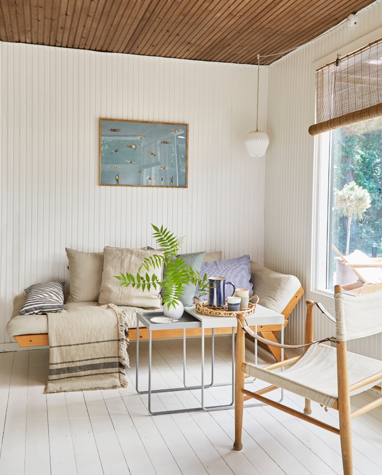 Daybed Karup Design. Stoel Fastrup. Bijzettafels Ikea. Hanglamp Le Klint. Poster Swimmers van PlakatCph. Mosselschaaltje Royal Copenhagen. Vaasje, gevlochten dienblad, kan en kopjes rommelmarkt. Overig onbekend. vtwonen special binnenkijken 06-2023 | productie Living Inside | fotografie Anitta Behrendt | styling Rikke Graff Juel