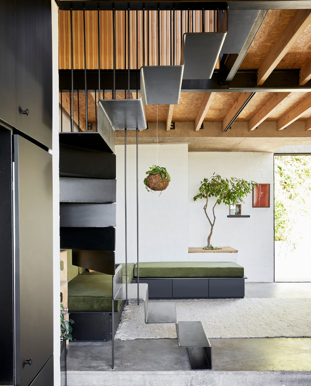 Stephen en Tanja's huis. Loungebank met bergladen en vaste plantenbak zelfgemaakt. Kokedama-hangplant Little Green Shop. Kunst Ana-Filipa Domingues (links) en Anke Loots. Kleed tweedehands. vtwonen special binnenkijken 03-2022 | productie Bureaux | fotografie Warren Heath | styling Sven Alberding