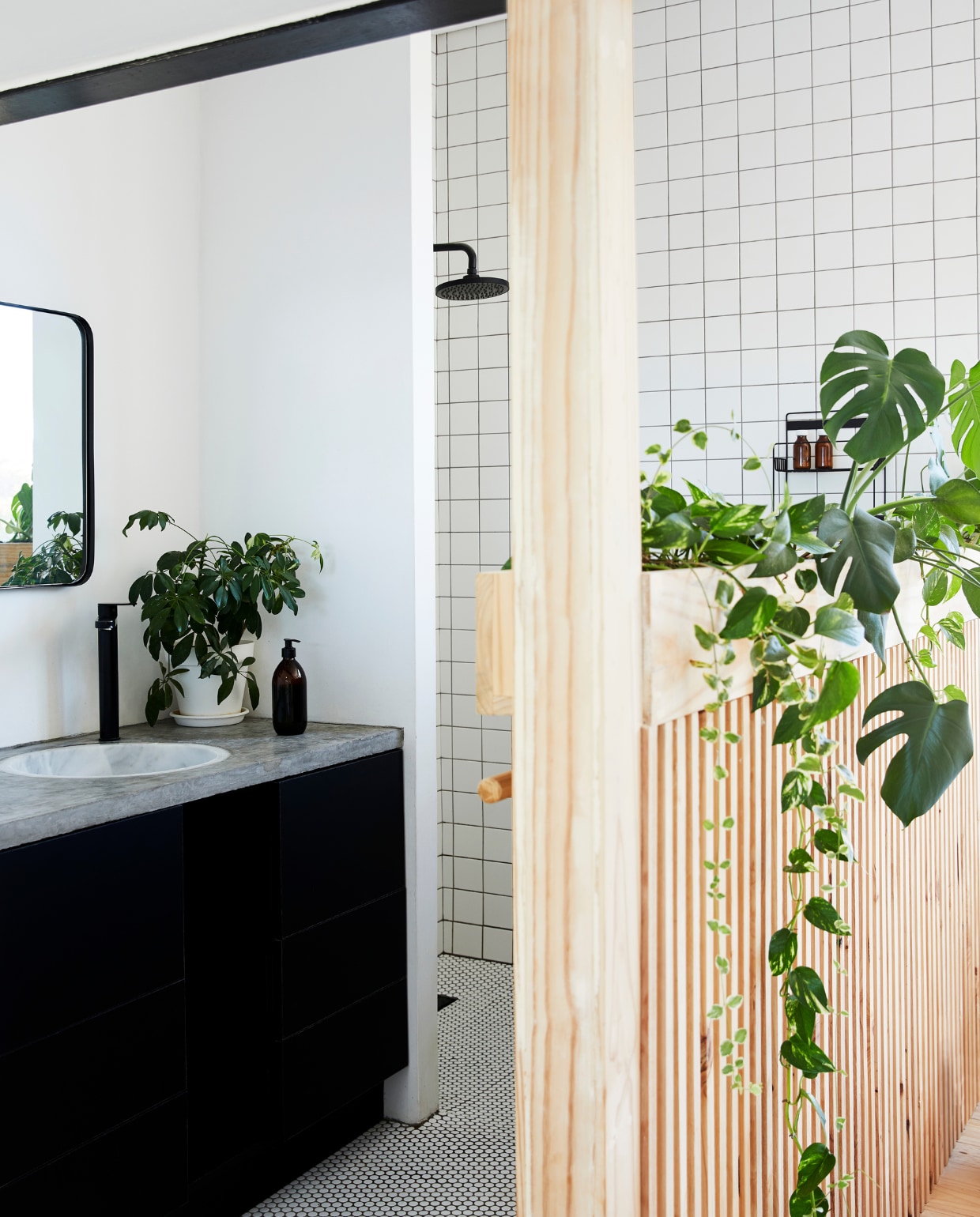 Stephen en Tanja's huis. In de ouderslaapkamer schermt een houten wand de inloopbadkamer af. Badmeubel Womag. Douche en kranen Gio Plumbing. vtwonen special binnenkijken 03-2022 | productie Bureaux | fotografie Warren Heath | styling Sven Alberding