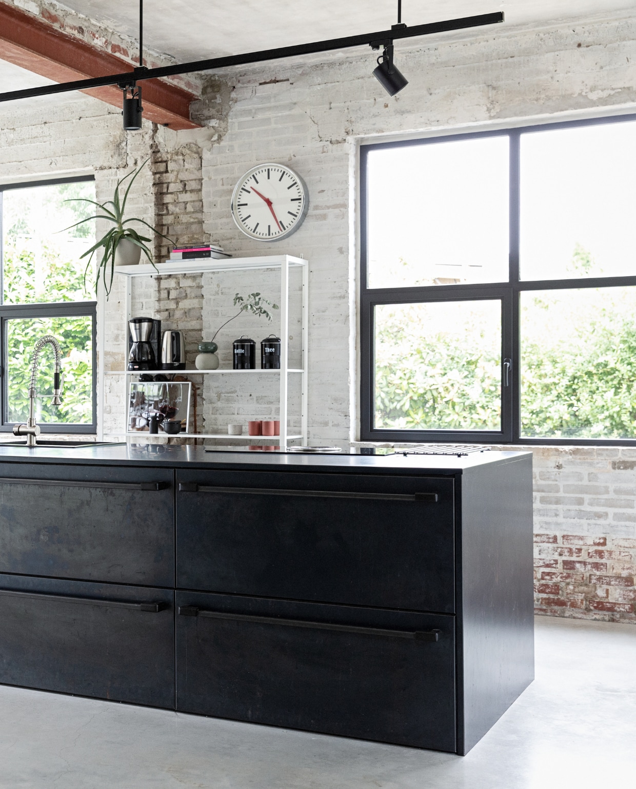 De keuken is een eigen ontwerp, binnenwerk op maat gemaakt door Marcel Hermans, beplating en werkblad van blauwstaal Schouren Metaal. Railarmatuur Venled. Toolbox Ferm Living. Krukken en open kast Ikea. Klok onbekend. Keukenblok eigen ontwerp, maatwerk, afgewerkt met geglazuurde tegels Praxis. Houten wand Okoume platen Bouwcentrum Driessen. Houten schappen koffiebar resthout meubelfabriek, deels geverfd in kleur Geordend van Histor. vtwonen 01-2022 | styling Ilona Jongepier | fotografie Dana van Leeuwen