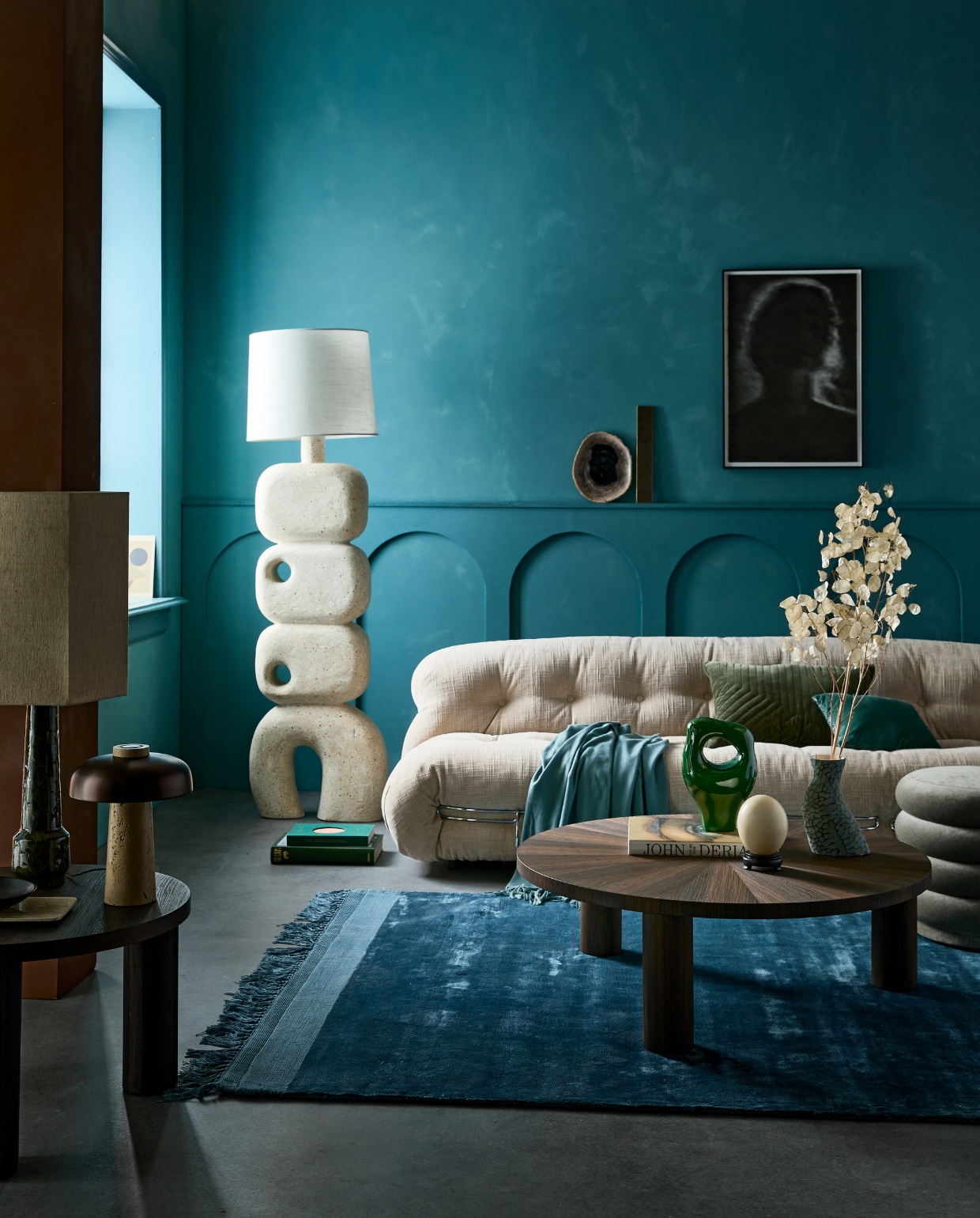 Kalkverf op de muur 87 Petrol, 2,5 liter € 126,- (lauthentique.nl). Lamp Reverse van Menu, travertijn en messing € 550,-(menuspace.com). Poef Faded Velvet van Ferm Living € 695,-, bank Soriana van Cassina, 250x101 cm (bxd) vanaf € 6063,- (edha-interieur.nl). Salontafel small van Ferm living, 41x65 cm (hxØ) € 949,-, salontafel large van Ferm Living, 33x100 cm (hxØ) € 1219,-, blauw vloerkleed van Zuiver € 440,-, groene tafellamp van HKliving € 222,95, zwarte kom van vtwonen € 6,15 (vtwonen.nl). Groen keramisch ornament € 49,95, blauw jacquard kussen Doris van HKliving, 30x40 cm € 37,95, lampenkap hexagoon medium € 75,-(hkliving.nl). Blauwe plaid, 140x190 cm € 45,99, travertijn plateau € 35,99 (zarahome.com). Grote sculpturale vloerlamp van microcement € 1150,-(lanena-home.com). Ingelijste polymer etching kunstfoto van Chantal Elisabeth Ariëns (kahmanngallery.com). Groen fluwelen kussen, 40x60 cm € 59,-(nordal.eu). Overig privébezit. vtwonen 01-2022 | styling Cleo Scheulderman | fotografie Jeroen van der Spek | decorbouw Milo Kol