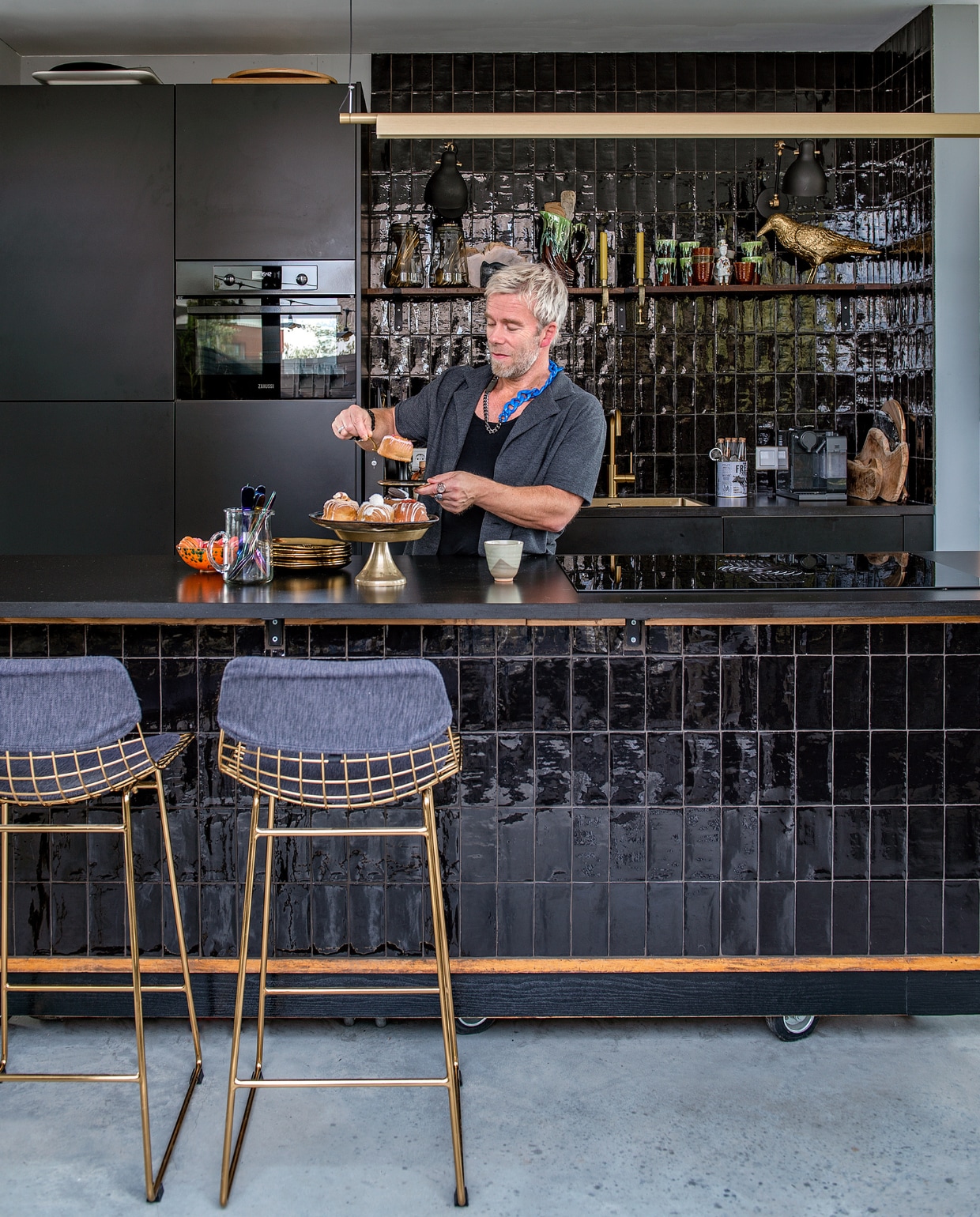 Toonbank Werkplaats 35. Barkrukken en gouden vogel HKliving. Tegels Tegelsonline. Gootsteen en kraan Keukenloods. Keramieken servies Spektakel Wonen, kaarsklemmen Madam Stoltz, gouden borden De Kaardebol, multicolour bestek Sluiz, koffiemaker Nespresso. Overig onbekend. vtwonen 10-2023 | fotografie Ton Bouwer