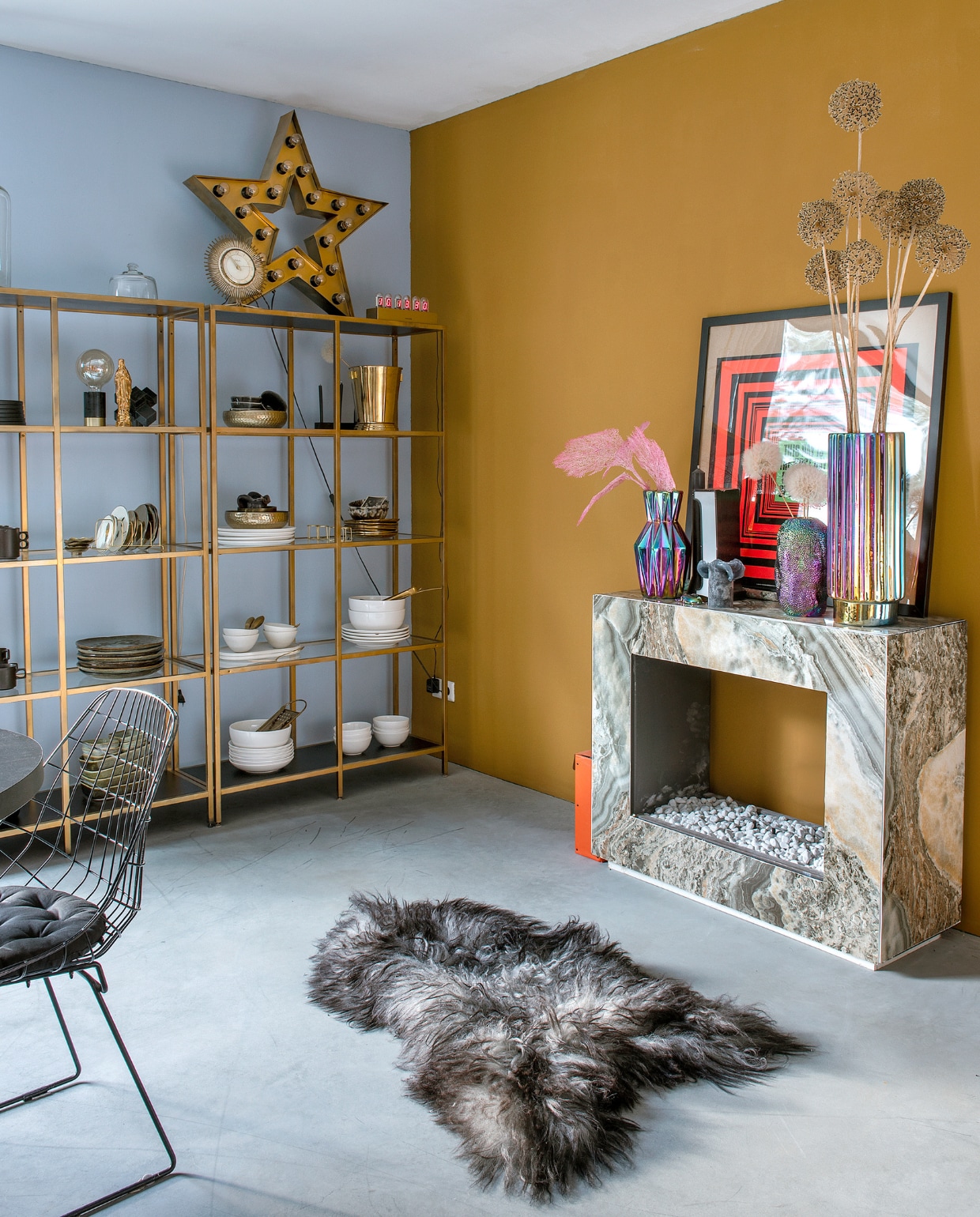 Kast Ikea, goud gespoten. Vacht Vachten van Terschelling, sterlamp Sissy-Boy, iriserende vazen de Bijenkorf. Schouw Karwei, zelf beplakt. Wit servies Dille & Kamille, zwart servies rommelmarkt. Aardewerken servies en bollamp Tica. Gouden Maria-vaasje Loic Concept Store, print Sluiz, draadstoel vintage. Muurverf Bright Skies van Flexa en Old Ocre van Pure & Original. Overig onbekend. vtwonen 10-2023 | fotografie Ton Bouwer