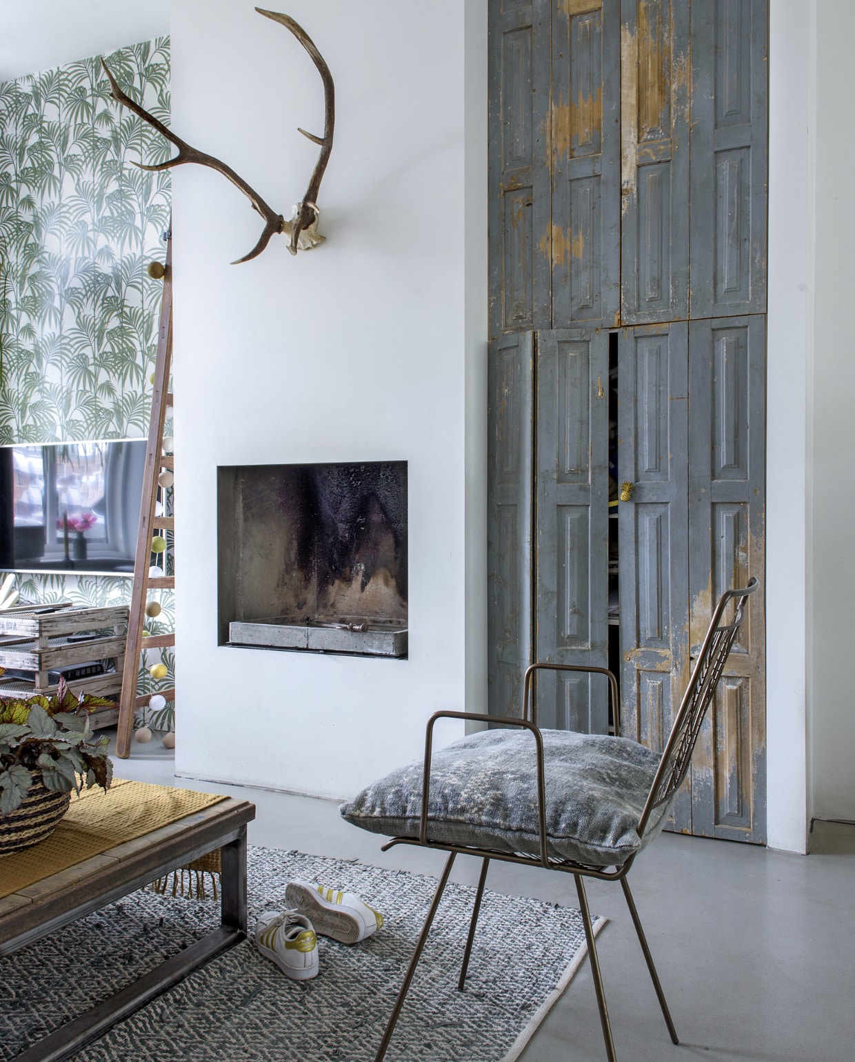 De kast is zelfgemaakt. Behang Honolulu van grahambrown.com. Stoel van madamstoltz.dk. Televisietafeltje gemaakt van oude bollenkratten. Oude fruitladder via marktplaats.nl, lichtsnoer cottonballlights.com, kussen van groenevingersdelft.nl, hertengewei gevonden op een Weense rommelmarkt. Deurknop ananas van doing-goods.com. Tafel zelfgemaakt van een steenschot, gele doek van tica.nl, vloerkleed van zusss.nl. vtwonen 01-2019 | fotograaf Ton Bouwer | styling Wendy Romeijn en Monique van der Pauw