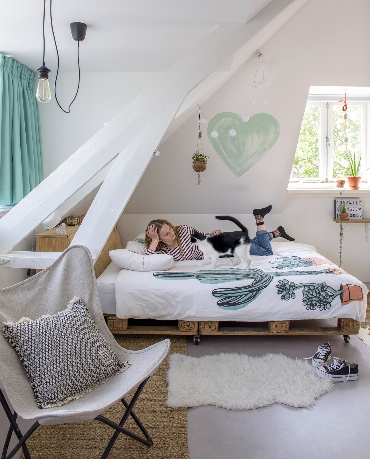 Lola’s bed is gemaakt van pallets. Op de vloer ligt Novilon Betonlook van vtwonen.nl/vtwonen-collectie. Het dekbed is van Hema. De vlinderstoel van Kwantum, het rieten kleed van Tica en het vachtje van Ikea. Herkomst kussen onbekend. vtwonen 01-2019 | fotograaf Ton Bouwer | styling Wendy Romeijn en Monique van der Pauw