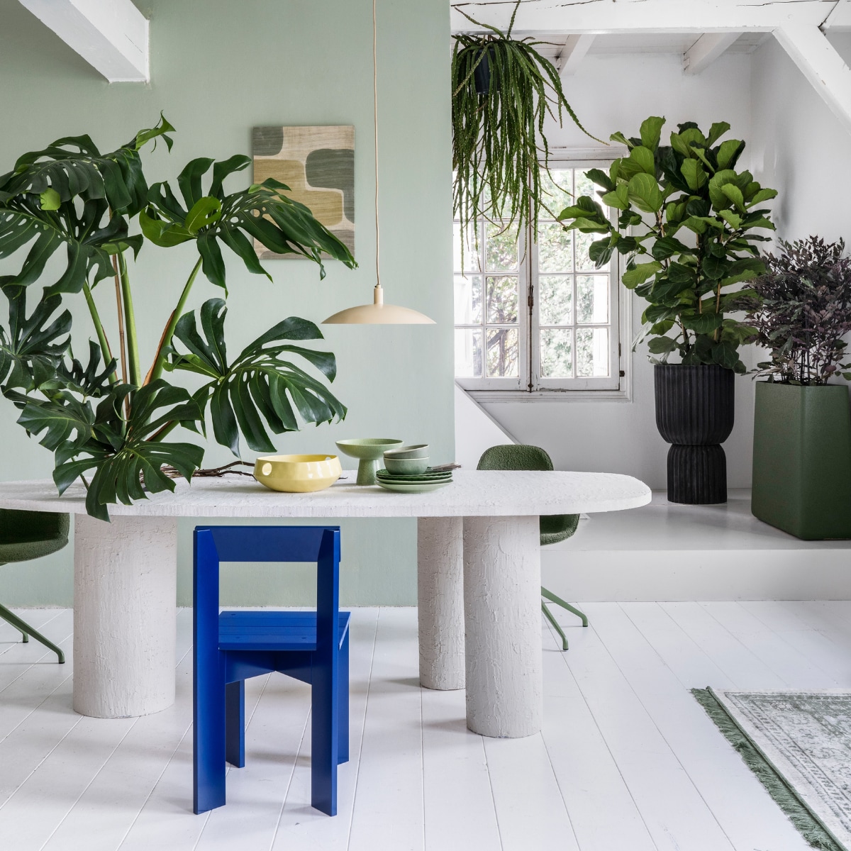 Plant op tafel Monstera € 195,-, hangplant Rhipsalis € 44,95, plant achter Ficus Lyrata € 195,-, pot, 45x88 cm (Øxh) € 295,-, plant Hami € 75,-, pot, 80x25x80 cm (bxdxh) € 495,-, achter de openslaande deur treurvijg € 125,- (bydennis.nl). Muurverf in nr. 58 van Lab Paint, 1 liter € 48,- (vestingh.nl). Tafel, prijs en maat op aanvraag (com-anders.nl). Vloerkleed van Zuiver, 240x170 cm, hanglamp van Urban Nature Culture € 119,- (vtwonen.nl). Draaibare stoel Albert Kuip € 349,- (zuiver.nl). Houten stoel Ark Chair van Ferm Living, 40x78x45,5 cm € 199,- (flinders.nl). Zitelementen € 215,- (loods5.nl). Wandkleed € 81,80 (urbannatureculture.nl). Keramieken geribbeld bord, set van 2 € 22,99,-, gespikkelde dinerborden, set van 2 € 26,99, groene keramieken schaal op voet van HKliving € 54,95 (vtwonen.nl), gele fruitschaal van Urban Nature Culture € 59,95 (urbannatureculture.com). vtwonen 03-2023 | Styling Marianne Luning | Fotografie Stan Koolen