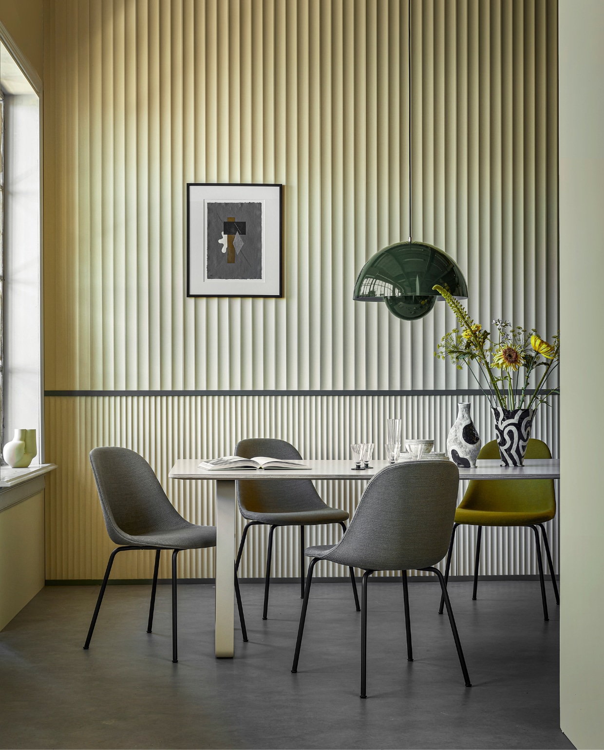 3D-wandpanelen van polyurethaan, boven W114 Valley XL, 200x25x1,5 cm (lxbxd) per stuk € 58,70, onder W109 Valley, 200x25x1,3 cm (lxbxd) per stuk € 58,70 (oracdecor.com), verf panelen Farrow’s Cream No.67 van Farrow &amp; Ball, per 2,5 liter € 97,- (paint-paper.nl). Verf lijsten Green Smoke No.47, per 2,5 liter € 97,- (farrow-ball.com). Tafel 70/70 van Muuto, eikenfineer en aluminium, 225x90x73 cm (lxbxh) € 2249,-, stoelen Harbour Side van Menu, per stuk € 660,-(hellochair.nl). Gele vaas Chubby € 85,-, zwart-witte aardewerken vaas Jessica Hans Shadow € 79,- (hay.nl). Glazen met voet klein, per stuk € 7,99, en groot, per stuk € 9,99, borden en kommen vanaf € 4,99 (hm.com). Kunstprint € 380,- (loods5.nl). Hanglamp Flowerpot € 576,-(andtradition.com). vtwonen 10-2022 | styling Kim van Rossenberg | fotografie Peggy Janssen