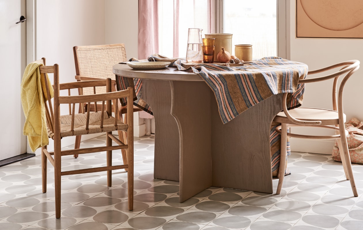 Tafel gemaakt naar eigen ontwerp en geschilderd in kleur Mexican Sand, prijs op aanvraag (com-anders.nl). Stoel met spijlen FD Møbler J81 Jørgen Baekmark vanaf € 880,- (letoile.store). Stoel met webbing zitting Nova € 239,- (vtwonen.nl). Stoel Thonet-model € 179,95 (dille-kamille.nl). Tafelkleed vanaf € 169,- (Libeco). Karaf € 20,-, water- glazen Salon Amber per stuk € 9,-, bord € 25,-, theedoek wafel in kleur Lemon € 10,75, tas met roze bloemen € 40,-(scandicliving.nl). Artwork aan de wand in kleur perzik, 60x80 cm € 595,-(hkliving.nl). Gordijn van voile stof Cosia in de kleur Orchid van Designers Guild, per meter € 93,- (wva.nl). vtwonen 05-2021 | styling Marlies Does | fotografie Bart Brussee