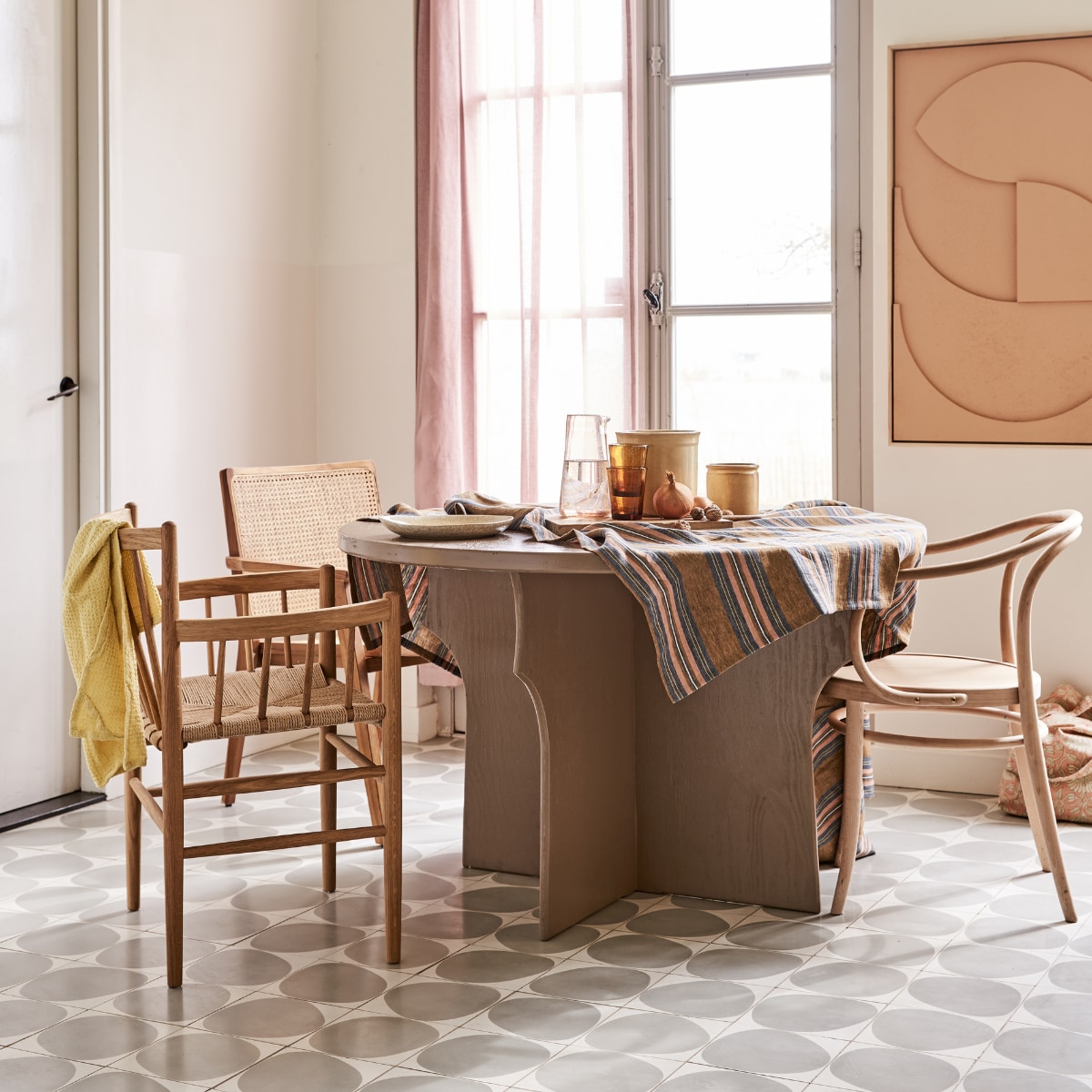 Tafel gemaakt naar eigen ontwerp en geschilderd in kleur Mexican Sand, prijs op aanvraag (com-anders.nl). Stoel met spijlen FD Møbler J81 Jørgen Baekmark vanaf € 880,- (letoile.store). Stoel met webbing zitting Nova € 239,- (vtwonen.nl). Stoel Thonet-model € 179,95 (dille-kamille.nl). Tafelkleed vanaf € 169,- (Libeco). Karaf € 20,-, water- glazen Salon Amber per stuk € 9,-, bord € 25,-, theedoek wafel in kleur Lemon € 10,75, tas met roze bloemen € 40,-(scandicliving.nl). Artwork aan de wand in kleur perzik, 60x80 cm € 595,-(hkliving.nl). Gordijn van voile stof Cosia in de kleur Orchid van Designers Guild, per meter € 93,- (wva.nl). vtwonen 05-2021 | styling Marlies Does | fotografie Bart Brussee