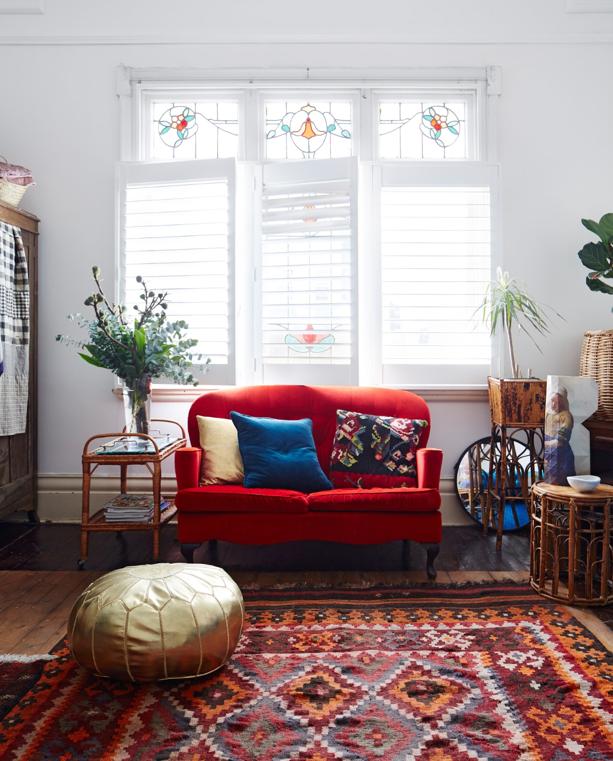Rode fluwelen bank vintage, zelf opnieuw bekleed. Goudkleurige leren poef Etsy. Overig vintage. vtwonen 06-2022 | styling Julia Green | fotografie Armelle Habib
