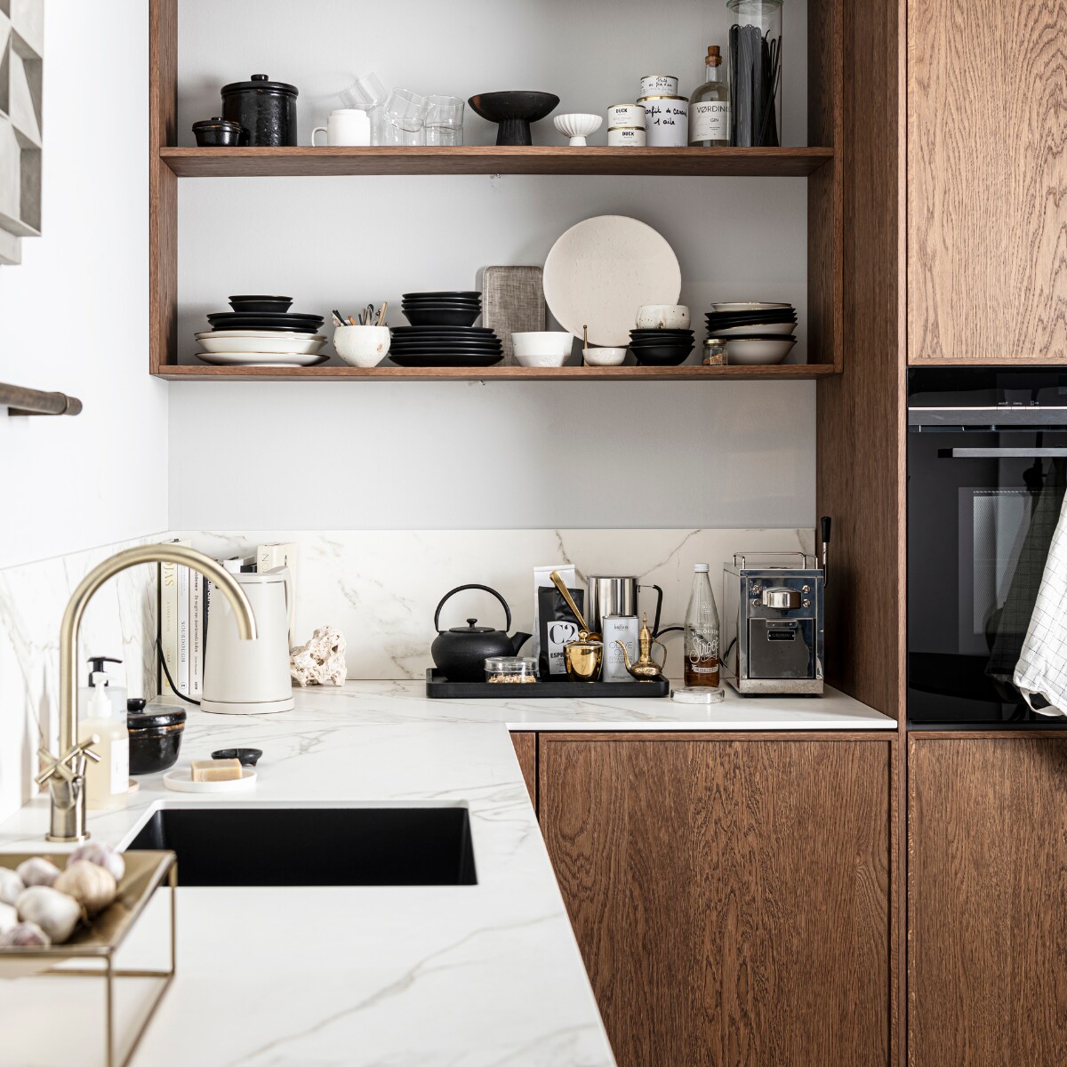 Keuken Dark Oak zoals getoond, exclusief accessoires € 19.950,- | M.m.v zarahome.com (opbergpot en bord met bordenstandaard), casagitane.com (schaal op poot), vtwonen.nl (glazen en servies van vtwonen), sjostrandcoffee.nl (koffiezetapparaat en melkopschuimer), vtwonen.nl (dienblad en theepot van Serax, waterkoker Sowden van Hay), thefinestore.com (dienblad). Overig privébezit. vtwonen 12-2021 | productie Tanja Saarberg | styling Kim van Rossenberg | fotografie  Sjoerd Eickmans