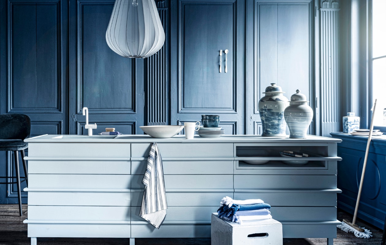 Blauw-witte potten, per stuk € 149,95, vierkante pot € 44,95, bezem € 13,95(loods5.nl). Witte pot van Serax bovenin links € 54,-, witte pot bovenin midden € 54,-,kraan prijs op aanvraag, witte schaal, prijs op aanvraag, vierkante kruk € 2241,-(badenbaden.nl). Donkere grote vaas boven op plank, set van 4 € 1936,-, 18e-eeuwsehouten vloer, per m² € 168,19 (pietjonker.nl). Gordijnstof 295 breed, per meter€ 103,- (wva.nl). Keukeneiland prijs op aanvraag (com-anders.nl). Vork en lepel€ 40,- (lisannevanzanten.nl). Hamamdoeken vanaf € 9,60 (ottomania.nl). Gestreeptetheedoeken, set van 3 € 9,99 (hm.com). Barkruk € 2174,- (covanderhorst.nl). Zeep€ 22,50, zeepborstel € 11,50, notitieboeken per stuk € 19,95 (maisonnl.com). Wittemok € 8,95, blauw-wit bord € 13,95 (hkliving.nl). Houten dienblad Zanat € 113,-(homestede.nl). In het midden bord van Leonardo, Ø 23 cm € 9,95, blauwe kom vanLeonardo, Ø 15 cm € 9,95, Balloon hanglamp van Bolia € 469,- (vtwonen.nl).Overig privébezit. vtwonen 07-2020 | styling Liza Wassenaar | fotografie Sjoerd Eickmans