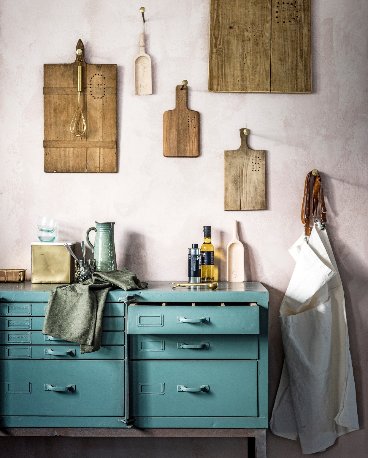 Snijplanken vanaf € 15,-, schepjes van hout € 3,-, stalen kast met lades € 750,- (Combitex). Snijplankje met letter K € 2,99(Ikea). Theedoek € 4,99, gouden garde € 19,99 (Sissy-Boy). Keukenschort Uashmama € 79,95, flesje olie € 15,95, flesje azijn € 8,25, kan € 15,95, grote goudkleurige siernagels € 6,95, goudkleurig kistje met deksel van marmer € 32,95, mandje € 12,95, glas € 8,95, koffieschepje met goudkleurige cliphouder € 4,50 (Nijhof). Blauwgroene glazen € 2,25, lepels set van 12 € 10,- (Household Hardware). vtwonen 04-2017 | styling Marlies Does | fotografie Sjoerd Eickmans