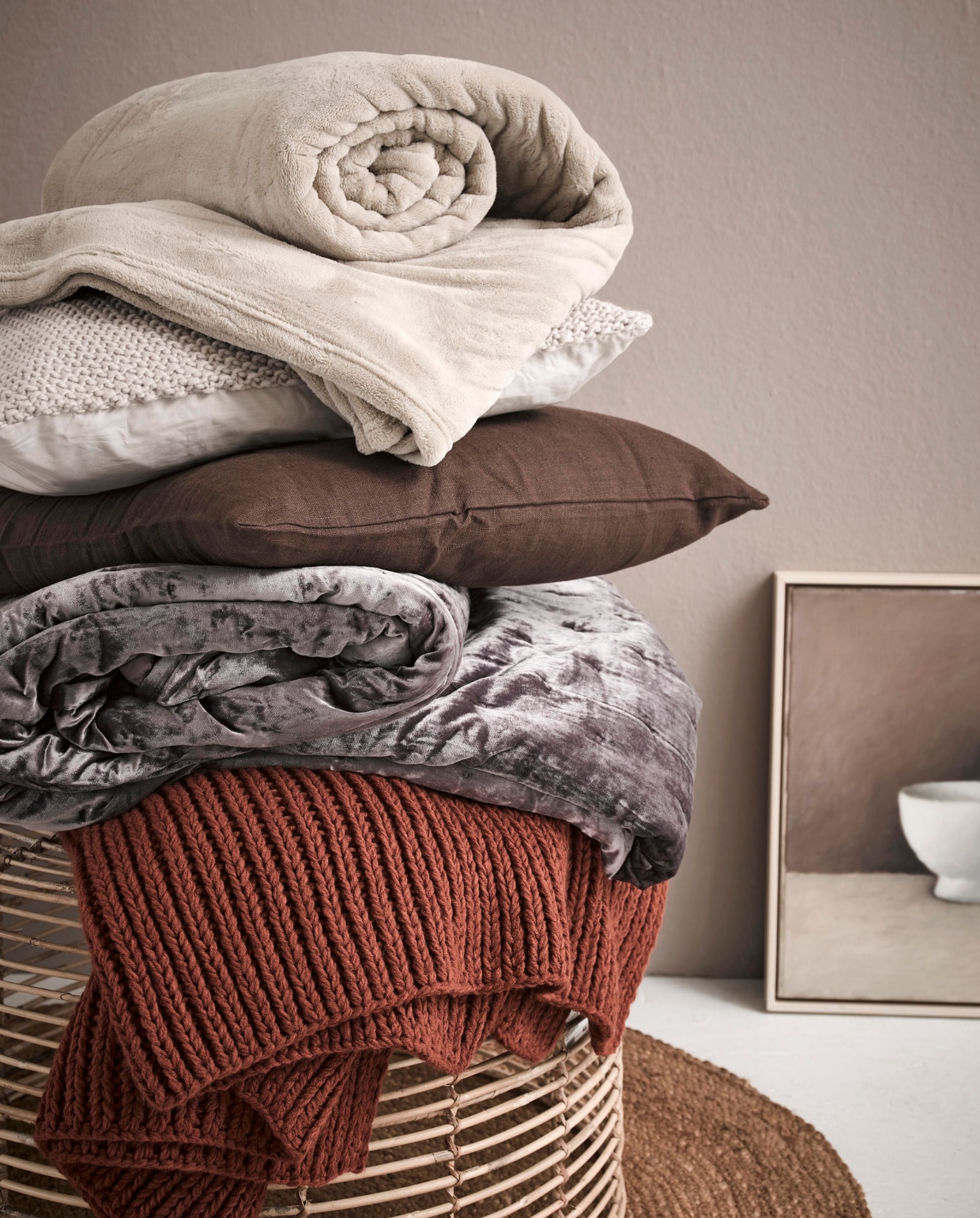 Op de wand matte krijtverf in kleur Somerset Mauve per liter € 37,20 (Pure &amp; Original). Rond juten kleed € 25,- (Kwantum). Bijzettafel Rattan vanaf € 44,99 (Trendhopper). Terrakleurige plaid € 39,99, velours sprei 260x260 cm € 129,-, wollen grof gebreid écru kussen € 19,99 (H&amp;M Home). Bruin kussen € 7,99, sprei Trattviva 230x250 cm € 29,95 (Ikea). Kunst van SBK Kunstuitleen Amsterdam. vtwonen 05-2018 | styling Fietje Bruijn | fotografie Alexander van Berge