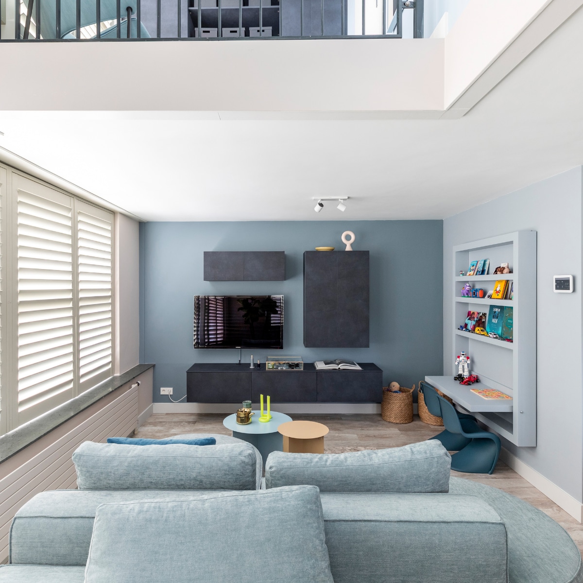 Flexa Creations muurverf bij wand met shutters Sandy Steps, achter tv Denim Drift, muur kinderhoek en kinderhoek Blissful Blue, plafond Denim Drift, muur entresol Kleur van het Jaar 2022 Bright Skies (flexa.nl). Shutters kleur Cream Grey, prijs op aanvraag (jasnoshutters.nl). Zwevend dressoir en kasten in kleur Lime Midnight, prijs op aanvraag (woninginrichting-aanhuis.nl). Elementenbank Loki van Studio Mik € 4683,-, vloerlamp Bolt van Tonone € 450,-, vloerkleed Haven van Bic Carpets op maat gemaakt, prijs op aanvraag (eijerkamp.nl). Blauwe bijzettafel van HKliving € 249,-, crèmekleurige bijzettafel van HKliving € 149,-, donkerblauw kussen Dot van Hay € 85,-, kopjes van HKliving € 8,99, theepot Bold &amp; Basic van HKliving € 49,95, junior kinderstoelen Panton van Vitra € 185,-, aan plafond begane grond dimlamp Runner 2 Spot van Philips € 89,99 (vtwonen.nl). Gele kaars Twist van Lex Pott € 29,95 (groenenakker.nl). Showcase box, per 2 € 206,- (polspotten.nl). Op dressoir opbergdoos vitrine van vtwonen € 44,95, kandelaars Lavender Tube van Hay € 18,- en Midnight Blue Tube van Hay € 15,- (vtwonen.nl). Papieren beestjes vanaf € 11,75 (assemblishop.com). Ornament Circle on Base van HKliving € 40,-, geel bord van HKliving € 12,50 (eijerkamp.nl). DIY-kinderspeeltafel met kast, prijs op aanvraag (remmers-design.nl). Manden Insvep, per stuk € 29,99 (ikea.nl). Op entresol studeerplek met kastensysteem in kleur Lime Midnight, prijs op aanvraag (woninginrichting-aanhuis.nl). Kunstwerken in deze uitvoering Vormen #10 van Adriano Oliveira € 151,-, Vormen #05 van Adriano Oliveira € 151,- (werkaandemuur.nl). Tafellamp Bolt van Tonone € 345,-, fauteuil Glider van Artifort € 2009,- (eijerkamp.nl). Opbergdozen Tjena, per stuk € 2,99 (ikea.nl). Overig privébezit. vtwonen weer verliefd op je huis seizoen 15 aflevering 10 | styling Marianne Luning | fotografie Margriet Hoekstra