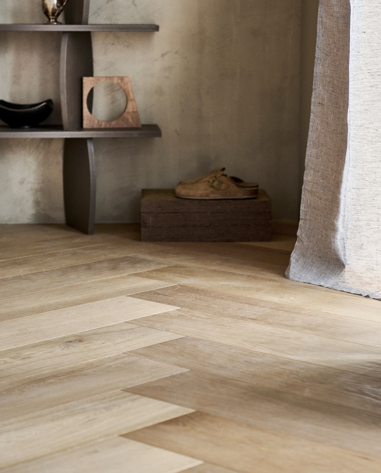 Eiken visgraat parketvloer blank geolied, v-groef aan beide zijdes, lamel 75x15x1,4 cm, inhoud per pak 1,8 m², per m² € 79,99, gordijn Frost in grijs, halftransparant met plooi, 140x270 cm (bxh) € 49,99. vtwonen 11-2023 | productie tanja Saarberg | styling Sanne Ketelaar | fotografie Sjoerd Eickmans