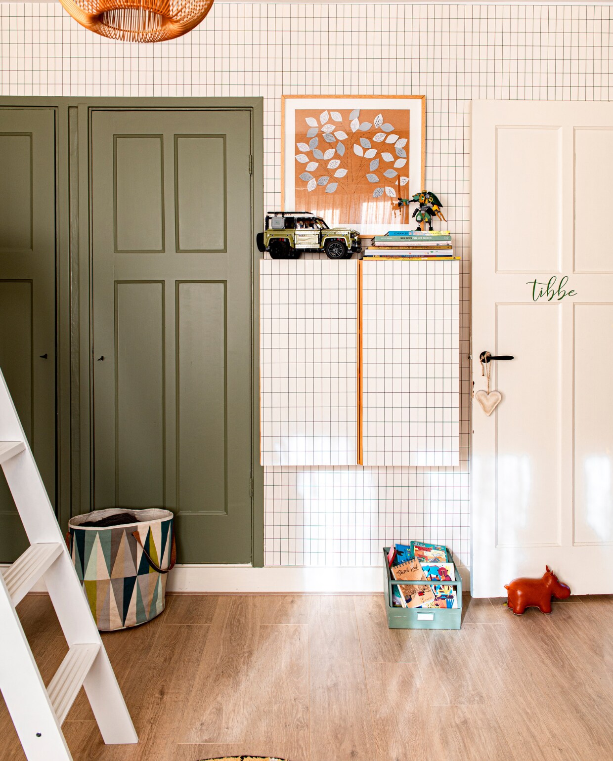 Geruit behang en wasmand Ferm Living, kast Bestå van Ikea, deurstopper Zuny. Hanglamp KidsDepot, auto Lego. Poster boom zelf gemaakt van allemaal wensblaadjes van familie en vrienden bij geboorte. Verfkleur kast Sage Green van Little Greene. vtwonen special DIY 7 | fotografie Caroline Coehorst