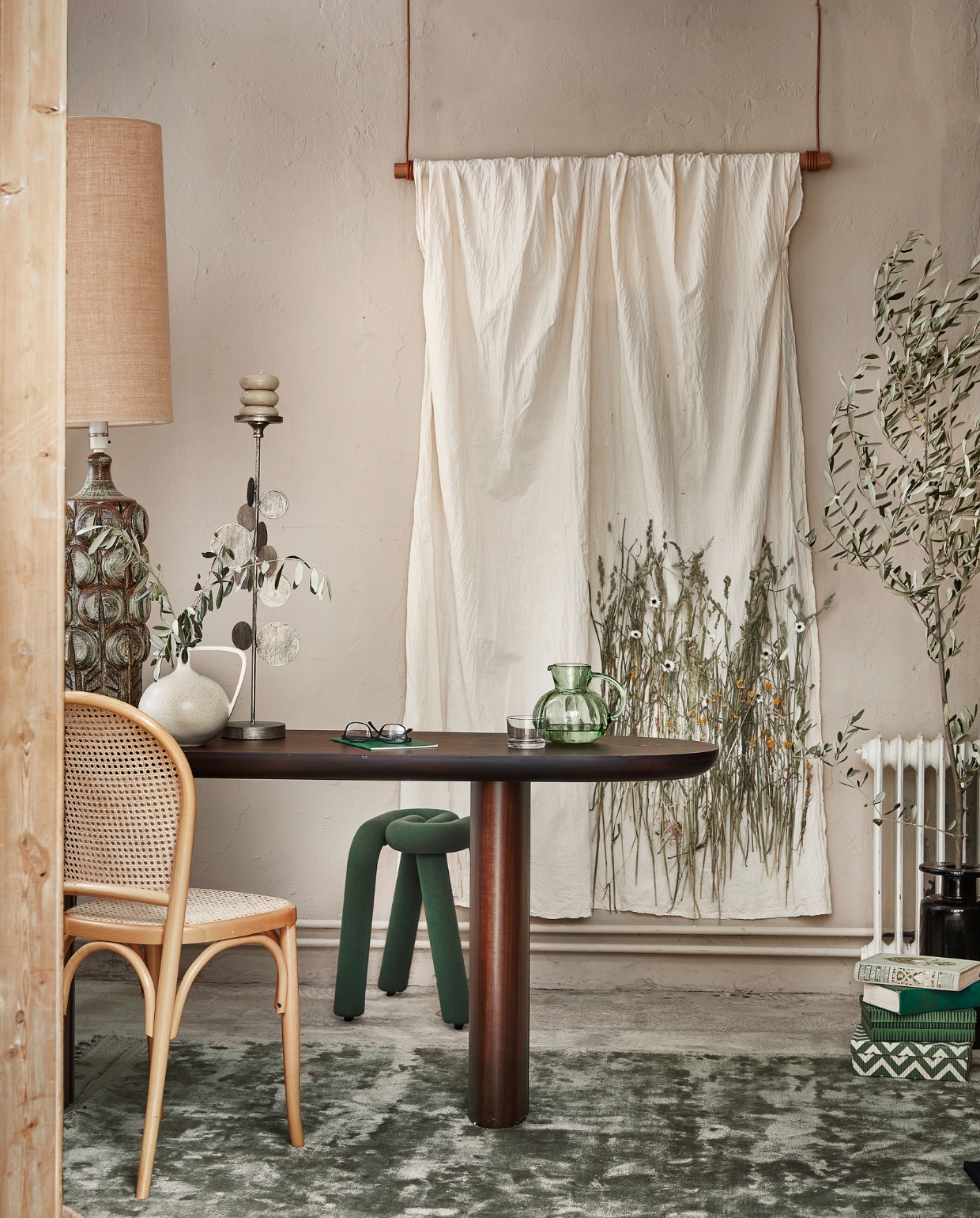Wanddoek van ongebleekt katoen met onder meer grassen, papierbloem, kerriebloem en hazenstaart, 230x160 cm prijs op aanvraag (loesjevanherp.studio). Houten kapstok Swing van Lind Dna, 110 cm € 250,-(etrais.nl).Eucalyptus- fineer tafel Hestia, 140x45x75 cm (bxdxh) € 1365,-, vintage keramieken tafellamp van Soholm Pottery € 1850,-, bruine glazen vaas van Serax € 129,- (cocooncollectables.nl). Witte keramieken vaas € 34,95, glazen karaf € 37,95 (hkliving.nl). Vloerkleed Ravel, 170x240 cm € 329,- (bepurehome.com). Kruk Bold van Moustache € 340,- (groenenakker.nl). Opbergdozen, set van 2 € 24,- (deensedingen.nl). Overig privébezit. vtwonen 10-2022 | styling Kim Timmerman | fotografie Peggy Janssen | assistentie Susanne van Schie