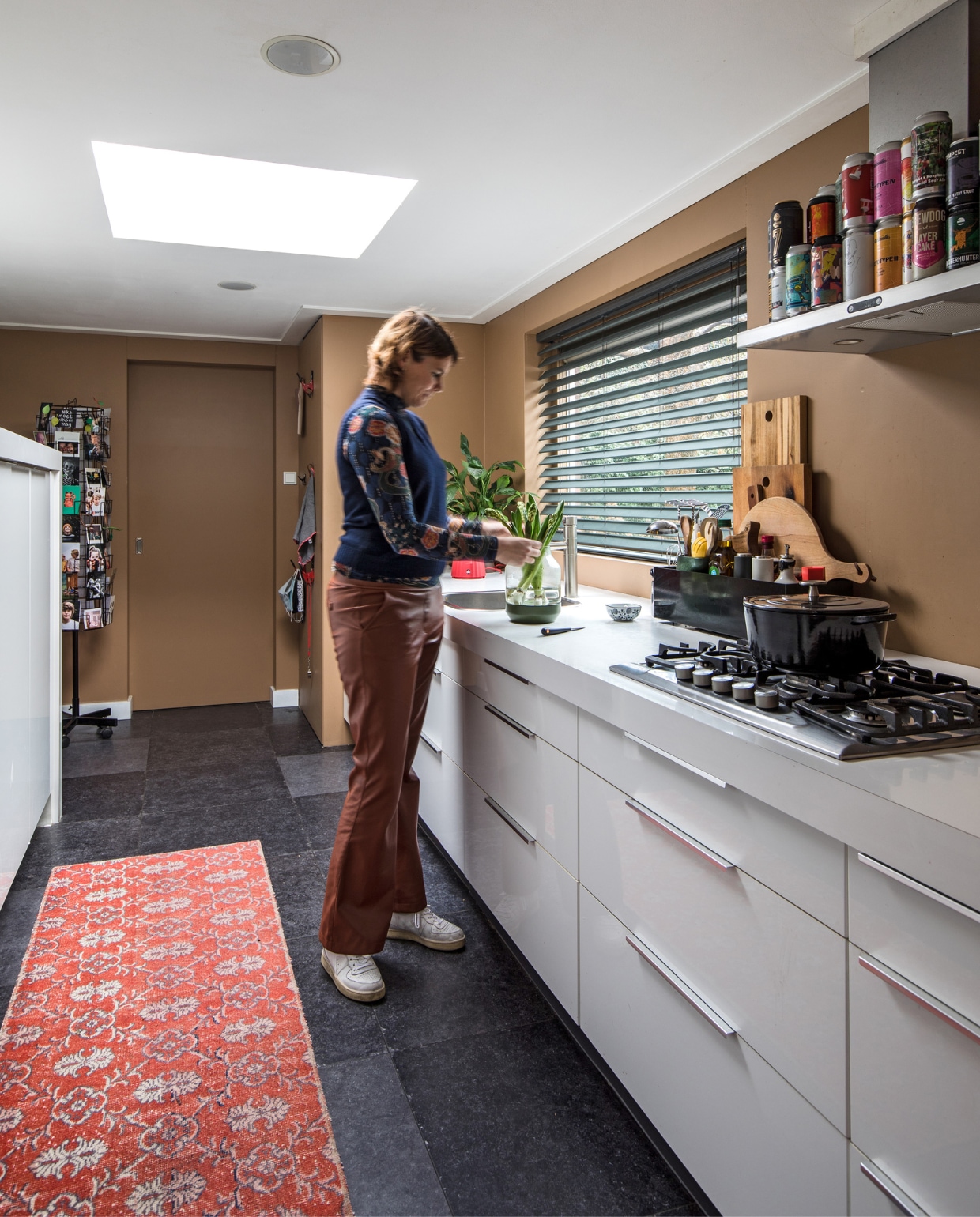 Vloertegels Kronos Ceramiche. Muurverf Spiced Honey Flexa. Rode loper Ikea. Keuken Faktum Ikea, door Rob vermaakt. Plant in hoek Ikea. Waterkoker Alessi, Bijenkorf. Vaas Muuto. Vlinderjaloezieën Bece raamdecoratie, Hubo. Verzameling IPA bierblikjes op afzuigkap. Planken zijn geschenken. Fornuis en afzuigkap Ikea. Pan Albert Heijn. vtwonen 10-2021 | productie en fotografie Corine Hoge Bavel