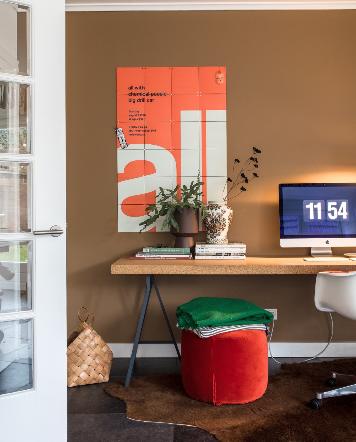 Scratch Acid &amp; All With Chemical People Punk Rock Concert geprint op Ixxi Your World. Bureau met blad van kurk Sinnerlig-collectie Ikea. Bloempot rechts Jysk. Plant tuincentrum. Kaststel gekregen van Maaikes oma. Beeldscherm Apple. Plastic bureaustoel Vitra PACC van Charles &amp; Ray Eames, Flinders. Poef Ikea Stockholm. Gestreepte plaid Ikea. Groene wollen plaid Hay. Mand Thuuz. Vacht Koldby, Ikea. vtwonen 10-2021 | productie en fotografie Corine Hoge Bavel