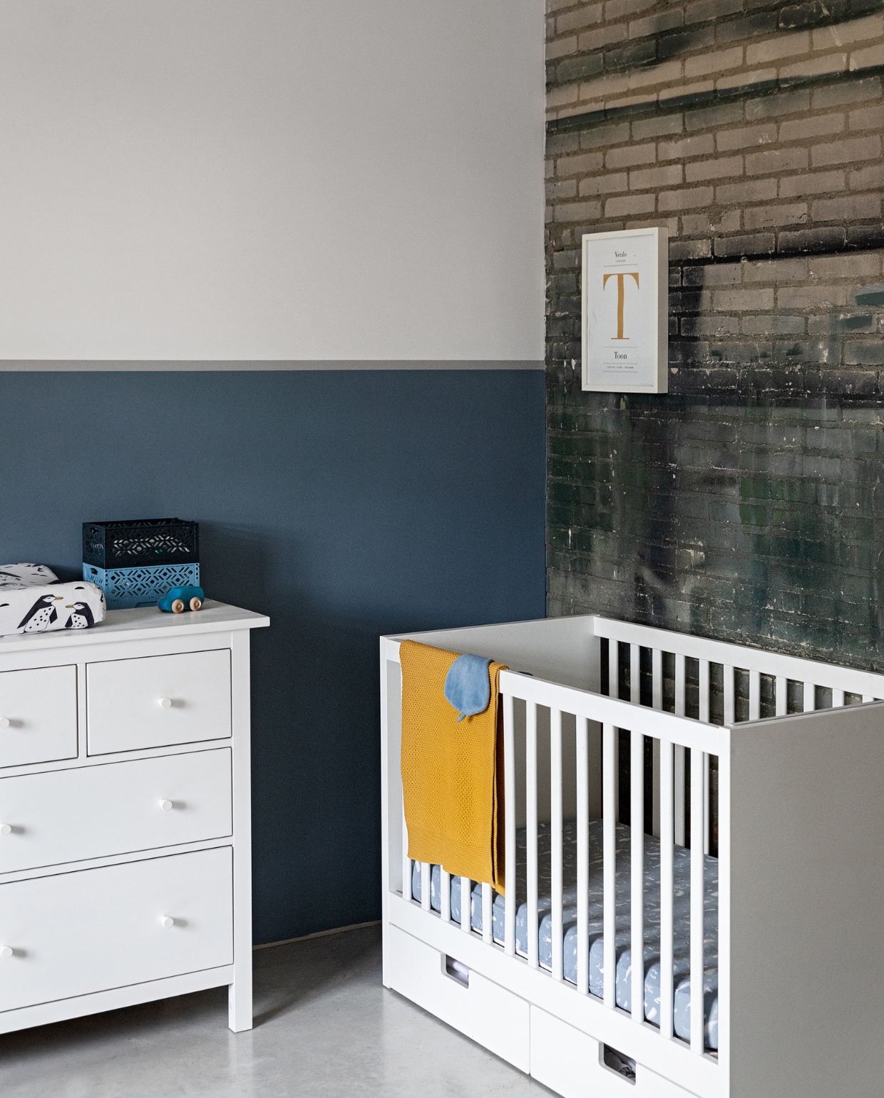 Commode en ledikant Ikea. Bakstenen muur met verfresten fabriek. Muurverf Real Indigo en Mild Marble van Flexa. Speelgoedauto Grimm. Bakjes Hema. Overig onbekend. vtwonen 01-2022 | styling Ilona Jongepier | fotografie Dana van Leeuwen | visagie Djolien de Kreij