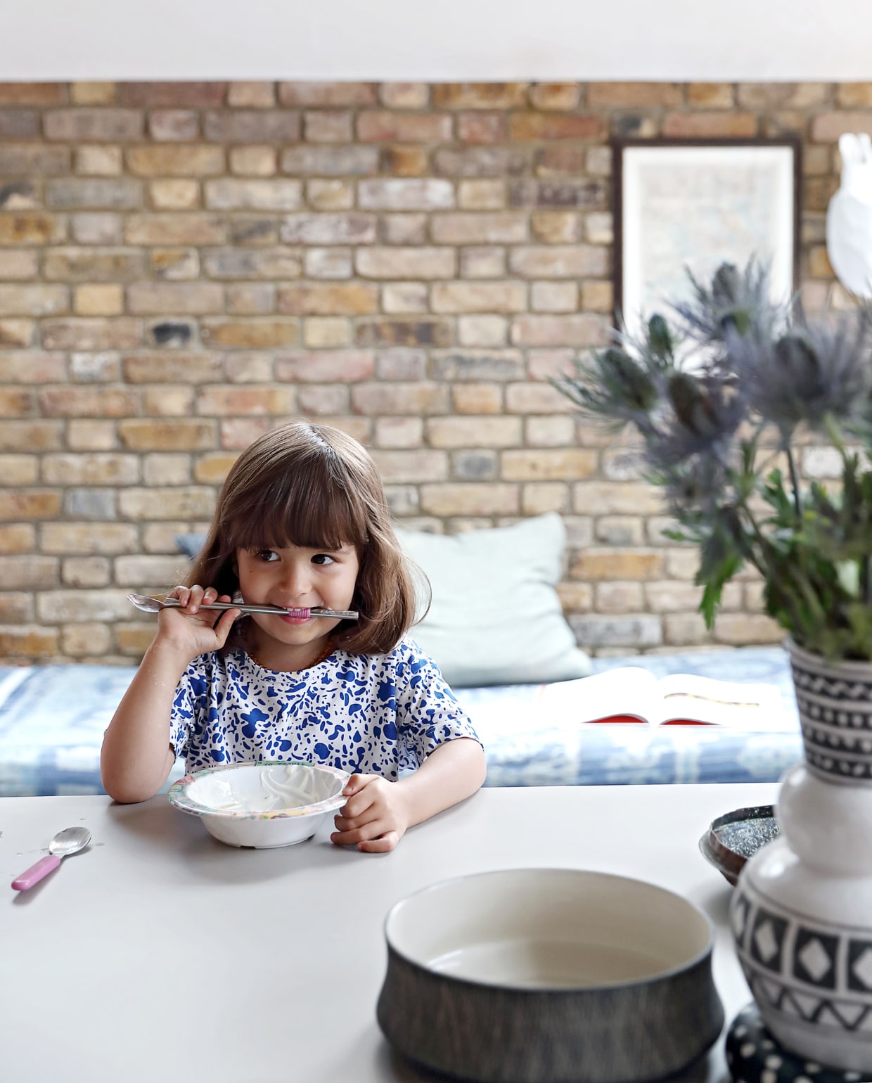 Indi zit aan het verrijdbare keukeneiland. Op de achtergrond is de zijaanbouw te zien die ook als logeerkamer wordt gebruikt, en die met een schuifdeur is af te sluiten van de keuken vtwonen special binnenkijken 03-2020 | productie Bureaux | styling Someday Studio | fotografie Elsa Young