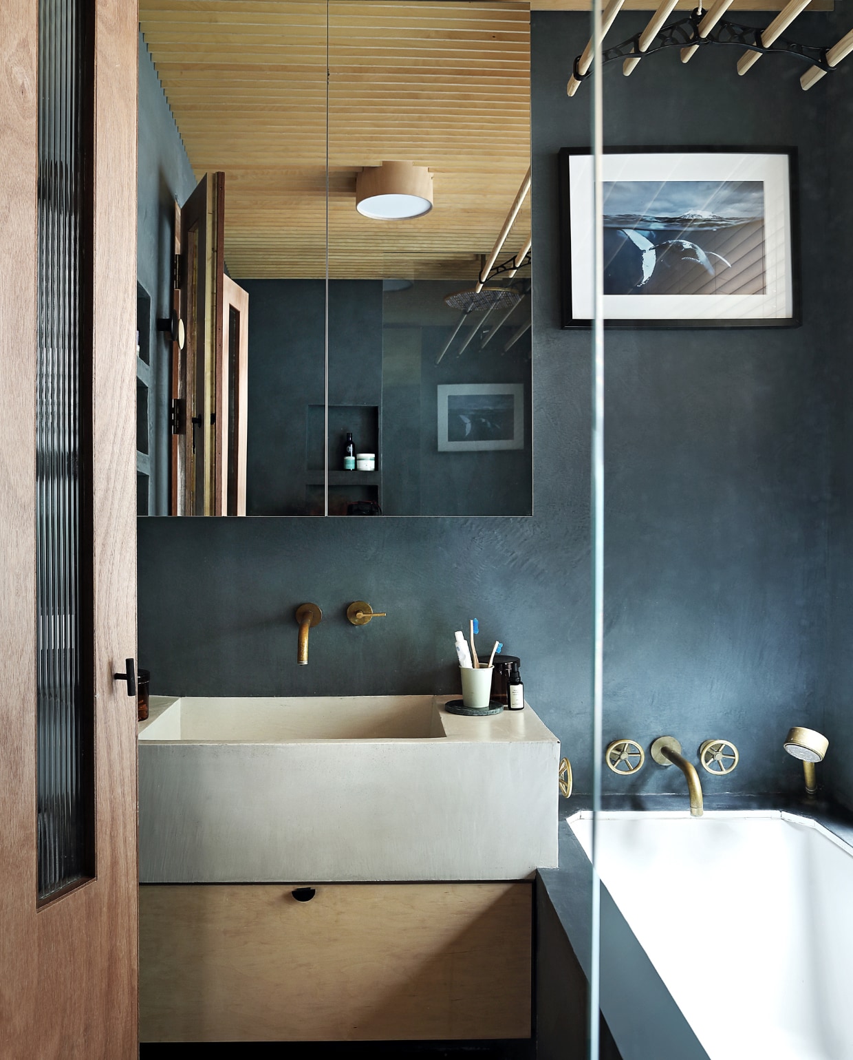 Liefde voor walvissen van de oudste dochter inspireerde bij het inrichten van de badkamer. De kleur van de tadelakt baseerden zij op walvisgrijs, gemengd via Tadelakt London. Bad en wastafel van Rise Design Studio, net als de kastjes, gemaakt door Liam Dryden. Kranen The Watermark Collection. Schilderij Natural History Museum.  vtwonen special binnenkijken 03-2020 | productie Bureaux | styling Someday Studio | fotografie Elsa Young