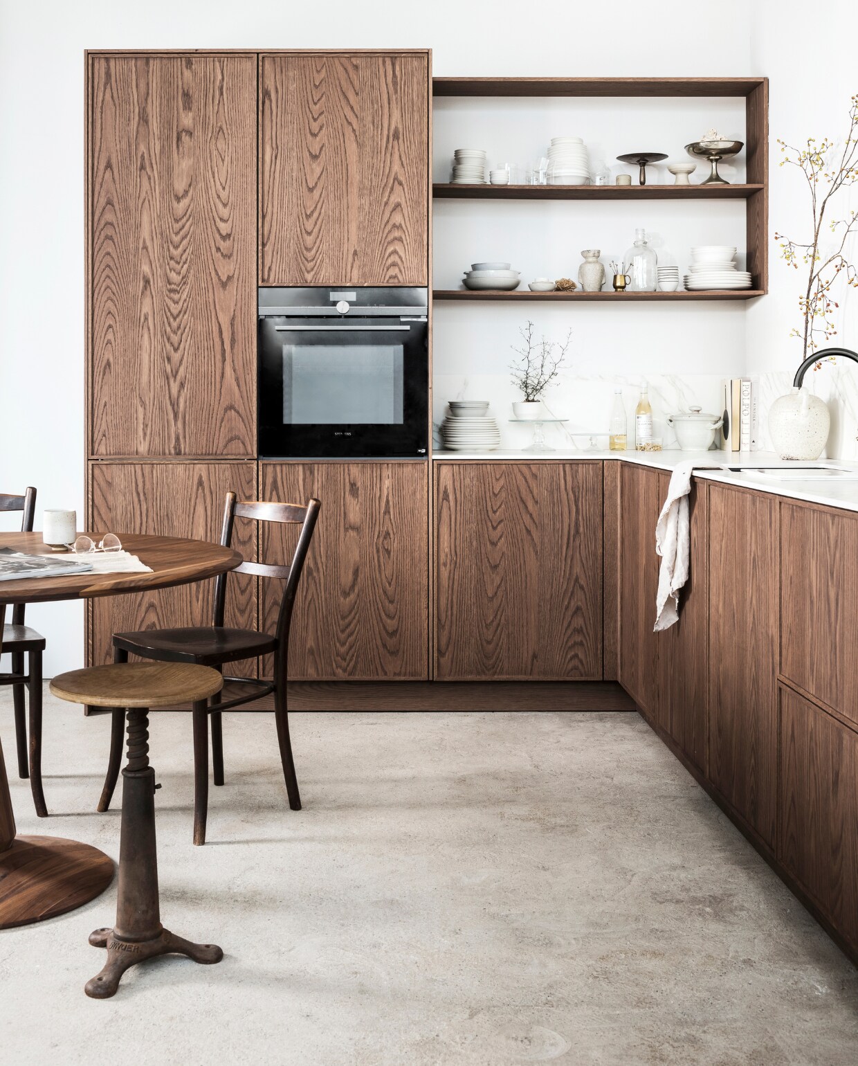DARK OAK Prijs zoals getoond vanaf € 17.500,- M.m.v.: mandemakers.nl, dezaakdesign.nl (tafeltje met marmeren blad, fotolijstje, rond dienblad, wit te vaas, hanglamp L amber t, stoelen en kruk), burbri.nl (koperen pannen), hm.com (linnen theedoek en schor t), villajipp.nl (af wasborstel), demachinekamer.nl (ronde walnoothouten tafel van Sav &amp; Okse), simonlevelt.nl (Slow Cof fee apparaat), kringloopwinkel (schaal op tafel), overig privébezit. vtwonen special vtverbouwen keuken 2022 | fotografie Sjoerd Eickmans, Peggy Janssen | styling Kim van Rossenberg