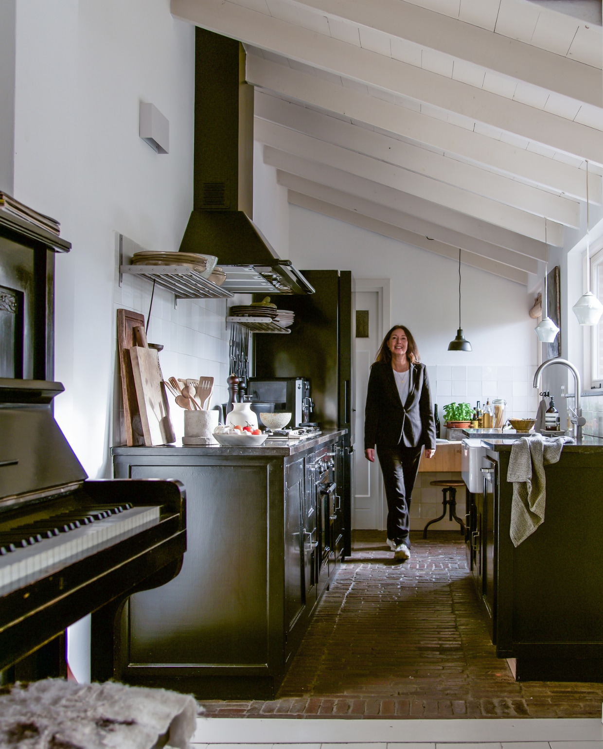 Kris in haar huis in Oegstgeest. Keuken zelfgemaakt. Vloer van klinkers uit de tuin. Accessoires uit de schuur van Kris’ ouders. Op de wand oude Friese Witjes. Piano Van Urk Rotterdam. Lampen herkomst onbekend. vtwonen 09-2021 | styling José Spaans | fotografie Barbara Groen