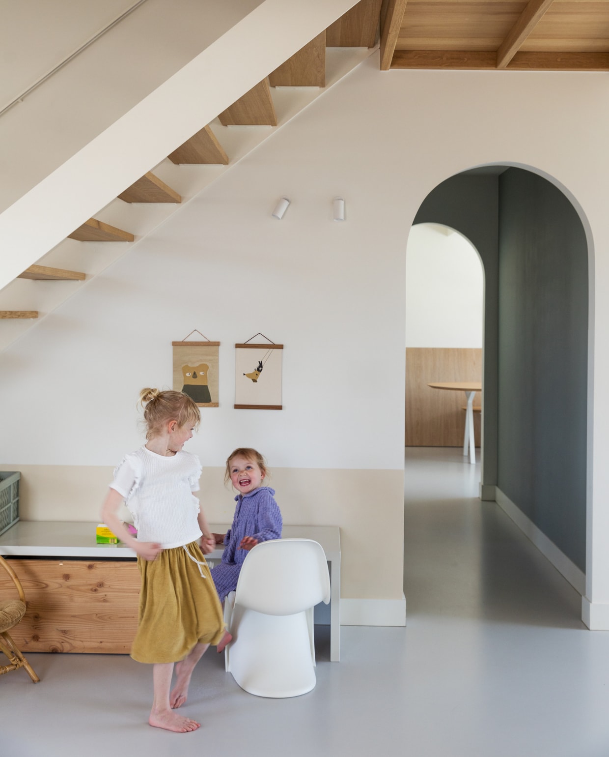 Opbergmeubel Bibelotte, stoel Panton van Vitra, rieten stoel Casa, posters Ted &amp; Tone. Muurverf lambrisering Joa’s White van Farrow &amp; Ball, muurverf gang Dark Sage van Sigma. Opbergbak Kwantum, wandlampen Modular, gietvloer kleurcode NCS S2000N van Alterieur. Overig onbekend. vtwonen 11-2023 | styling Ilona Jongepier | fotografie Dana van Leeuwen